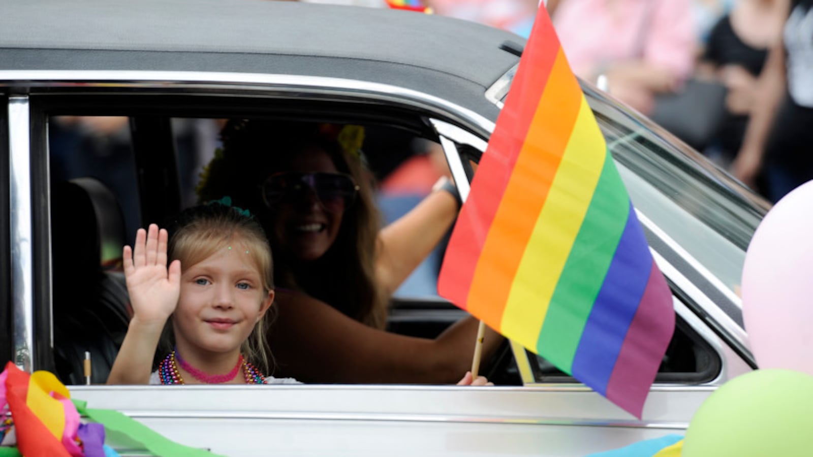 A child waves a a rainbow flag out of a window during the Denver Pride Parade along Colfax Avenue in 2018.