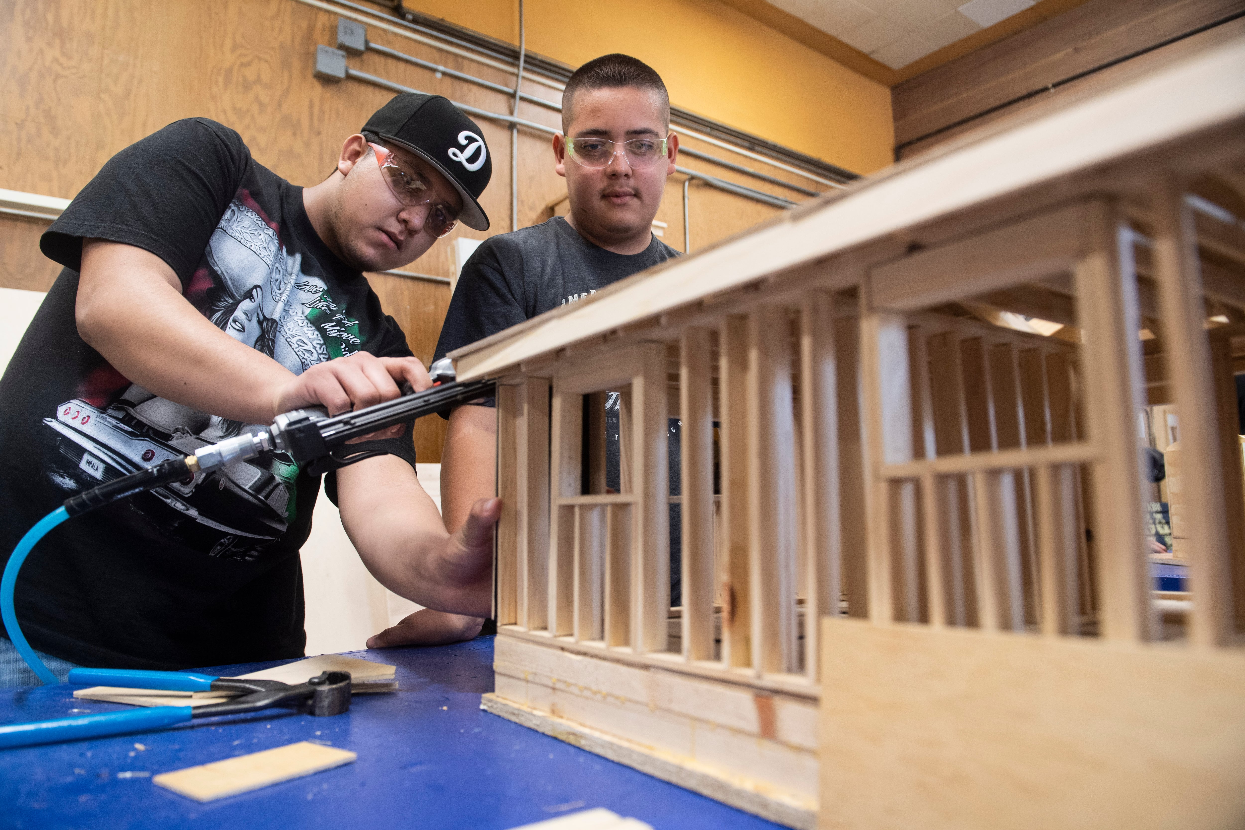 Two male students work on a building model.