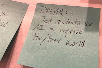 A grey sticky note with pen hand writing on a pink table.
