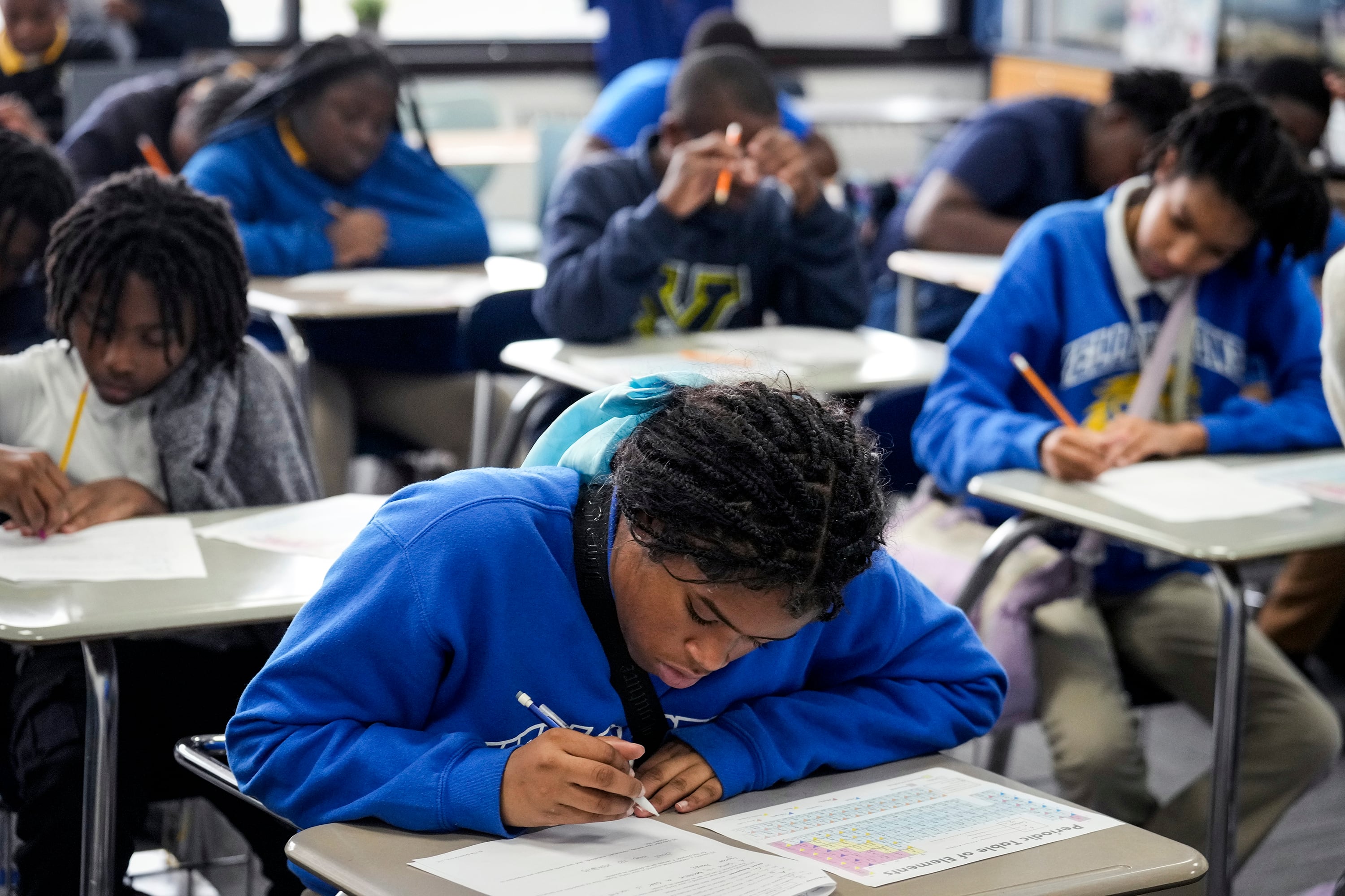 A photograph of a classroom full of Black high school students completing tests at their desks.
