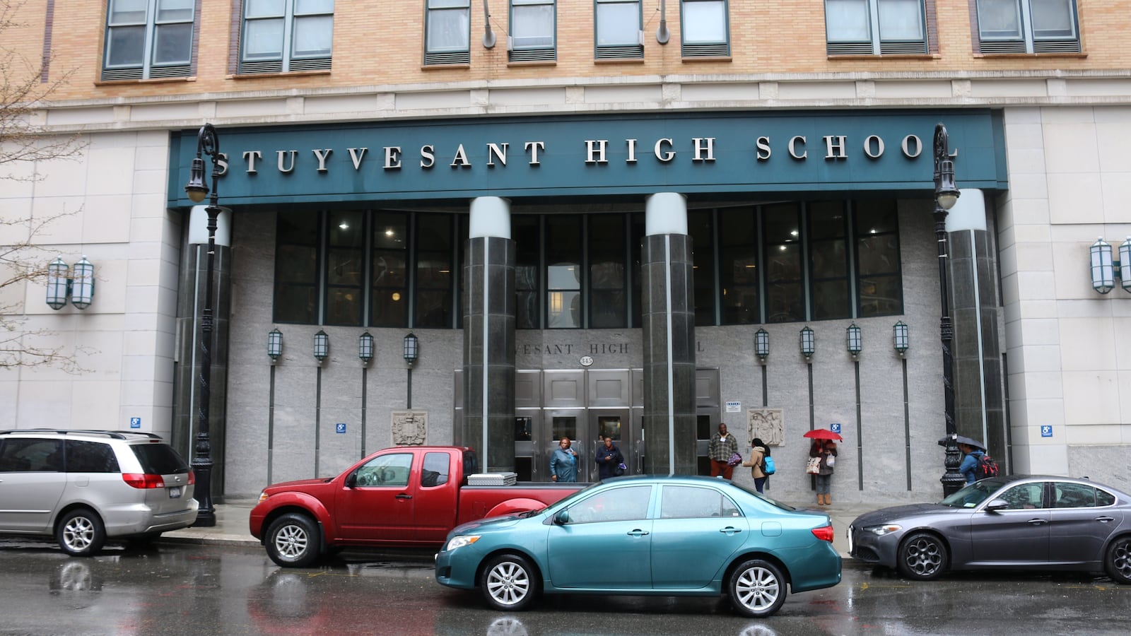 The exterior of a school with several cars out front