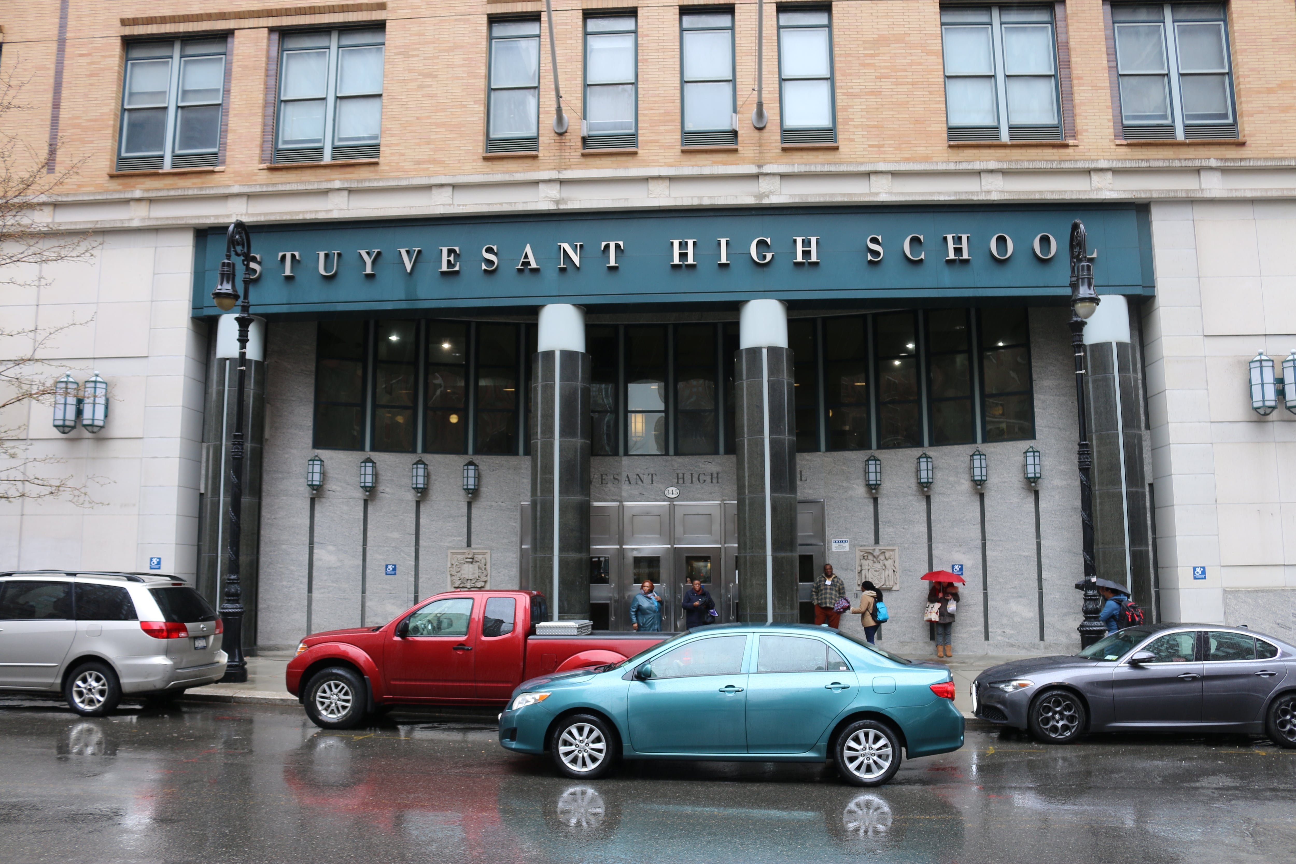 The exterior of a school with several cars out front