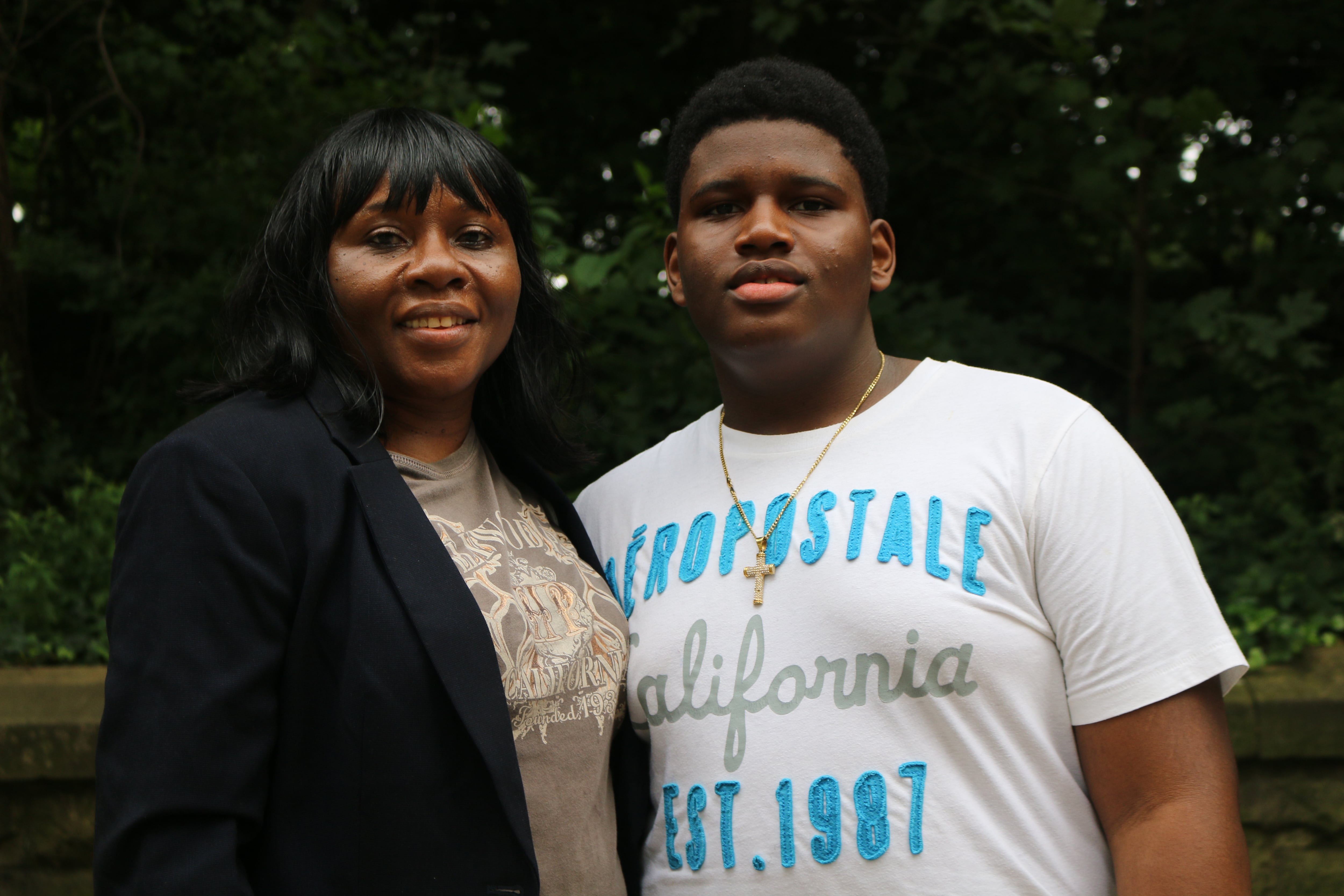 A mother stands next to her teenage son