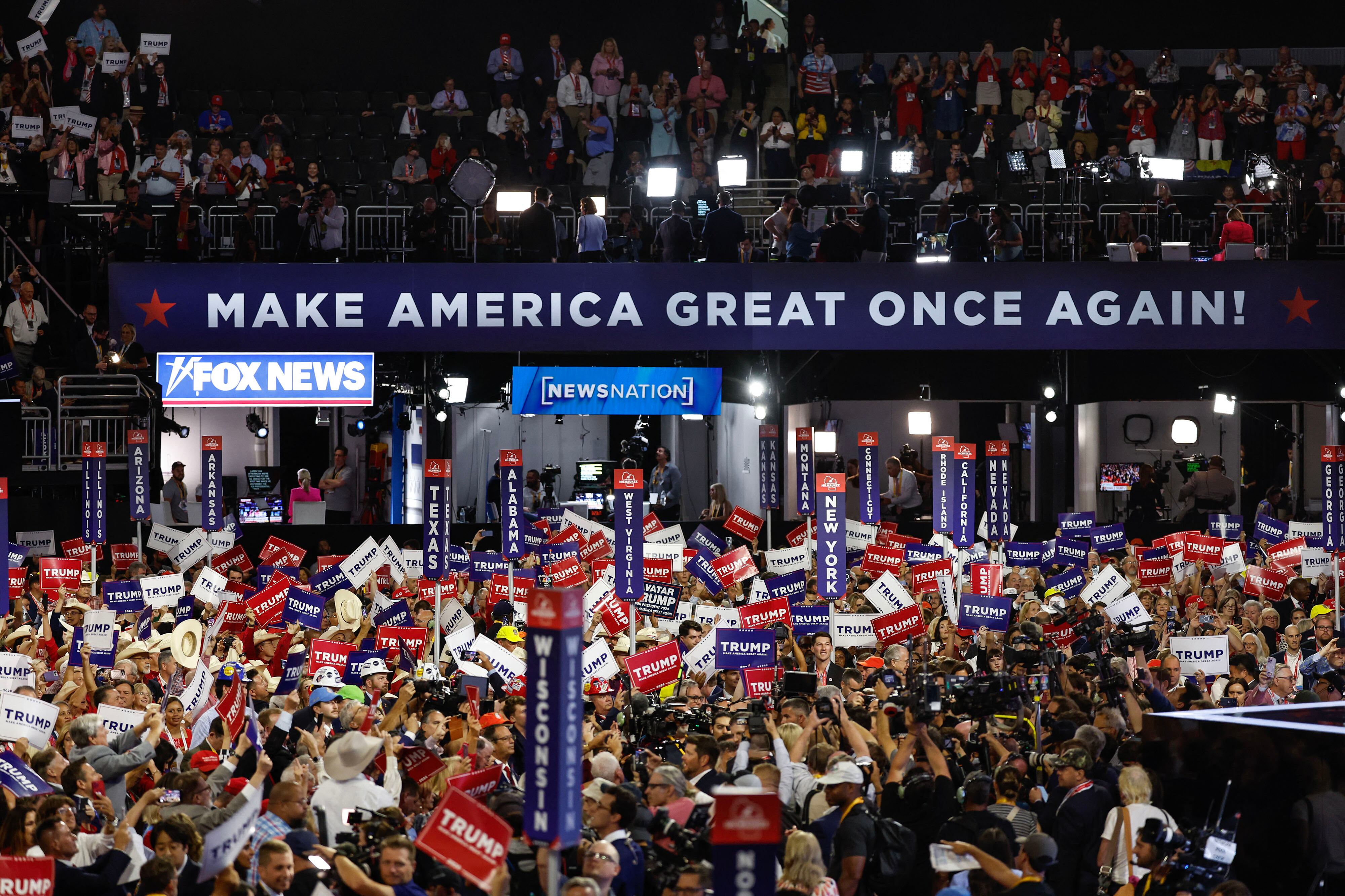 A large crowd gathers inside of a convention center on two different levels.