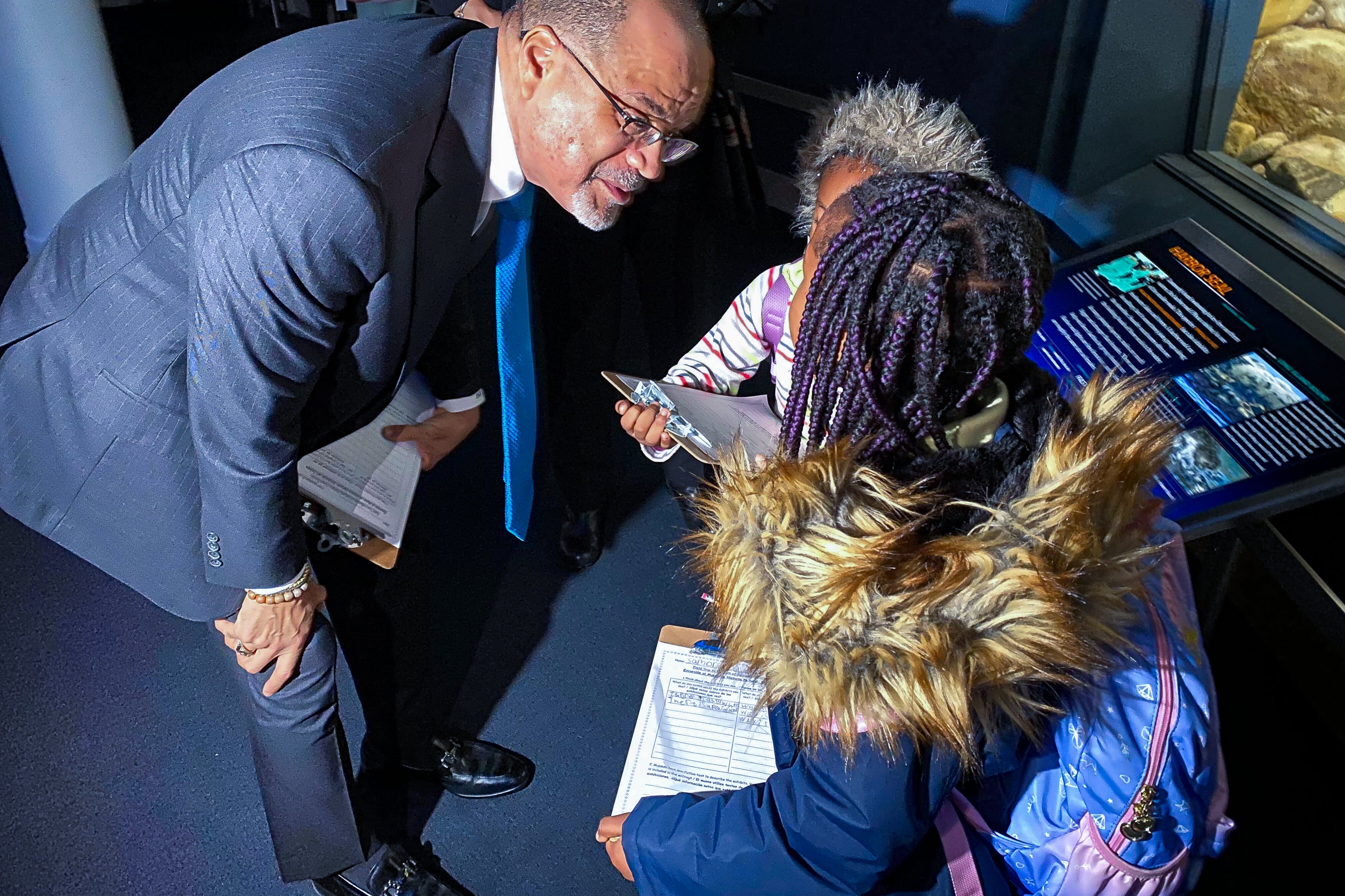 A man bends down to talk to a young girl in the museum of natural history.