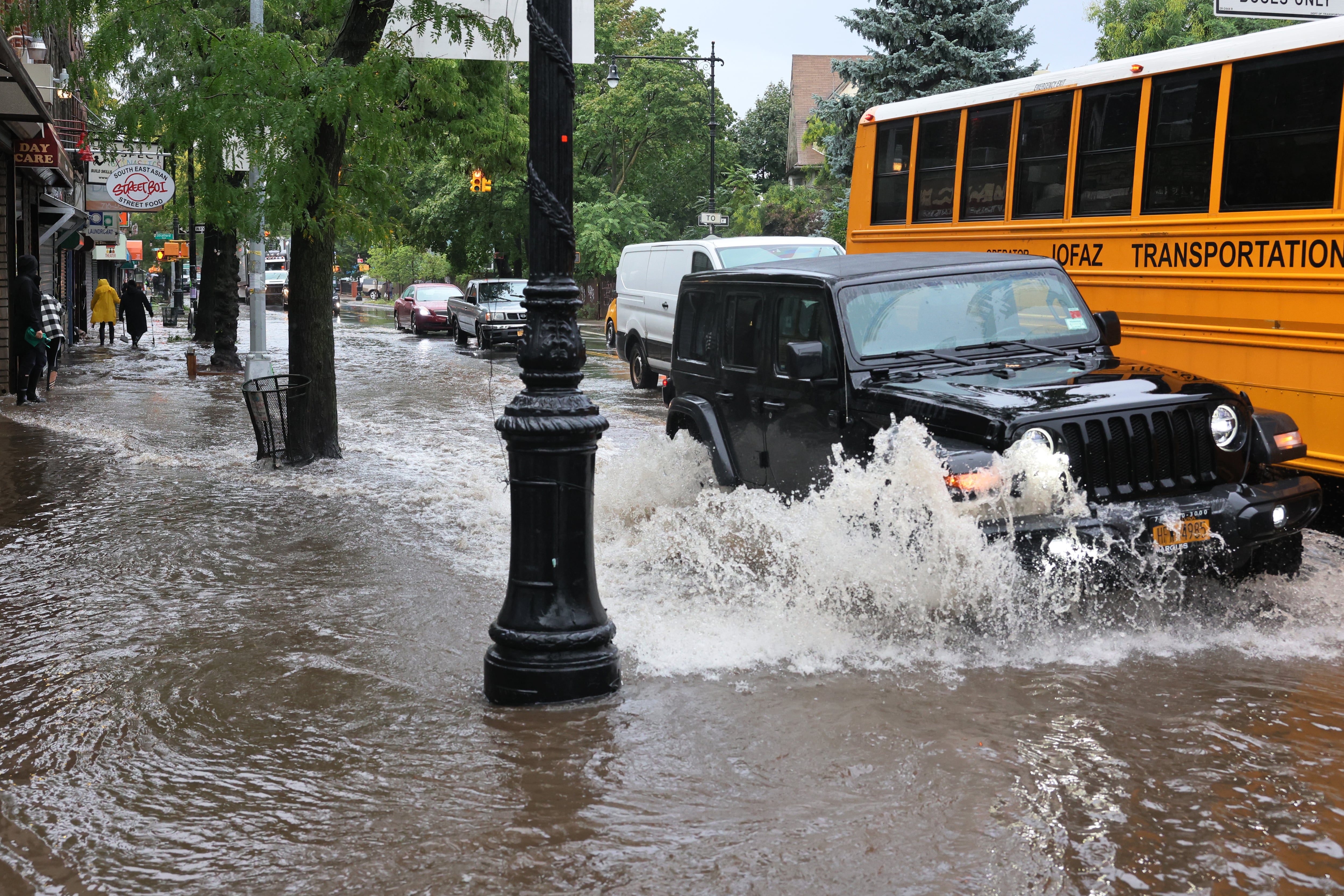 A Jeep kicks up a splash on a flooded street