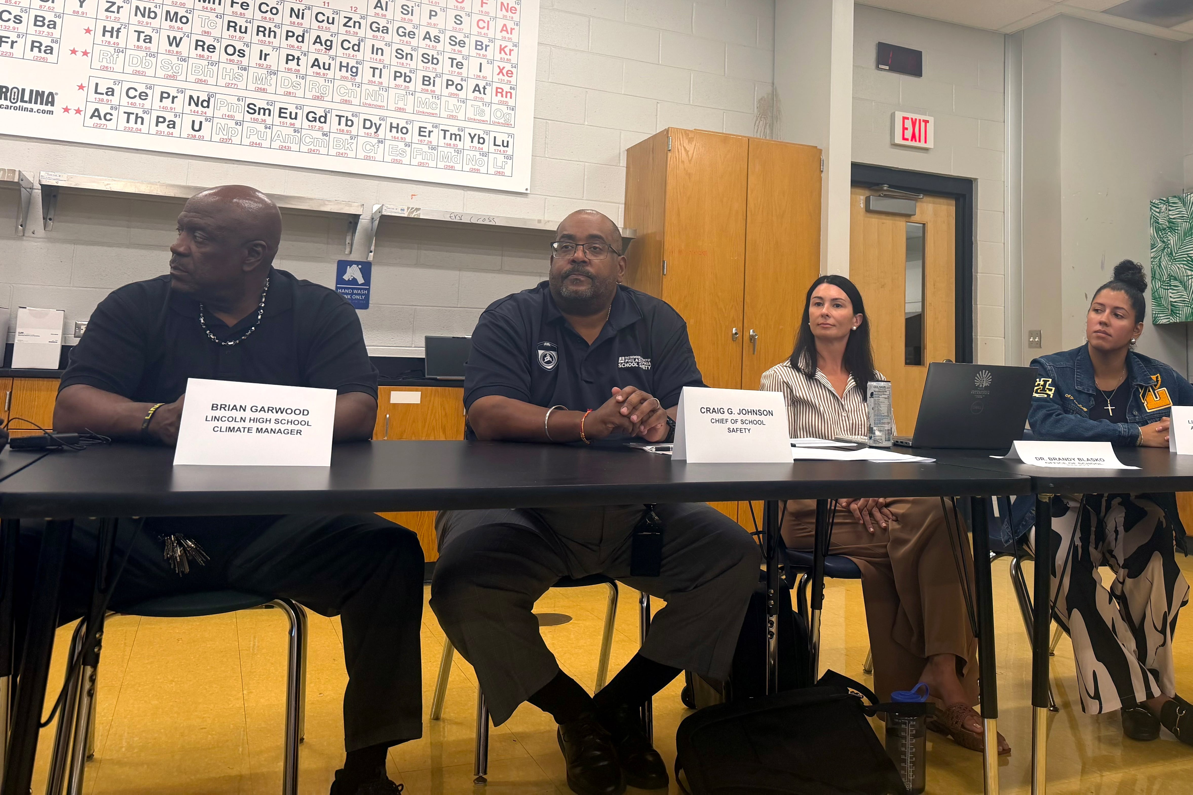 Two men and two women sit at a table with their names.