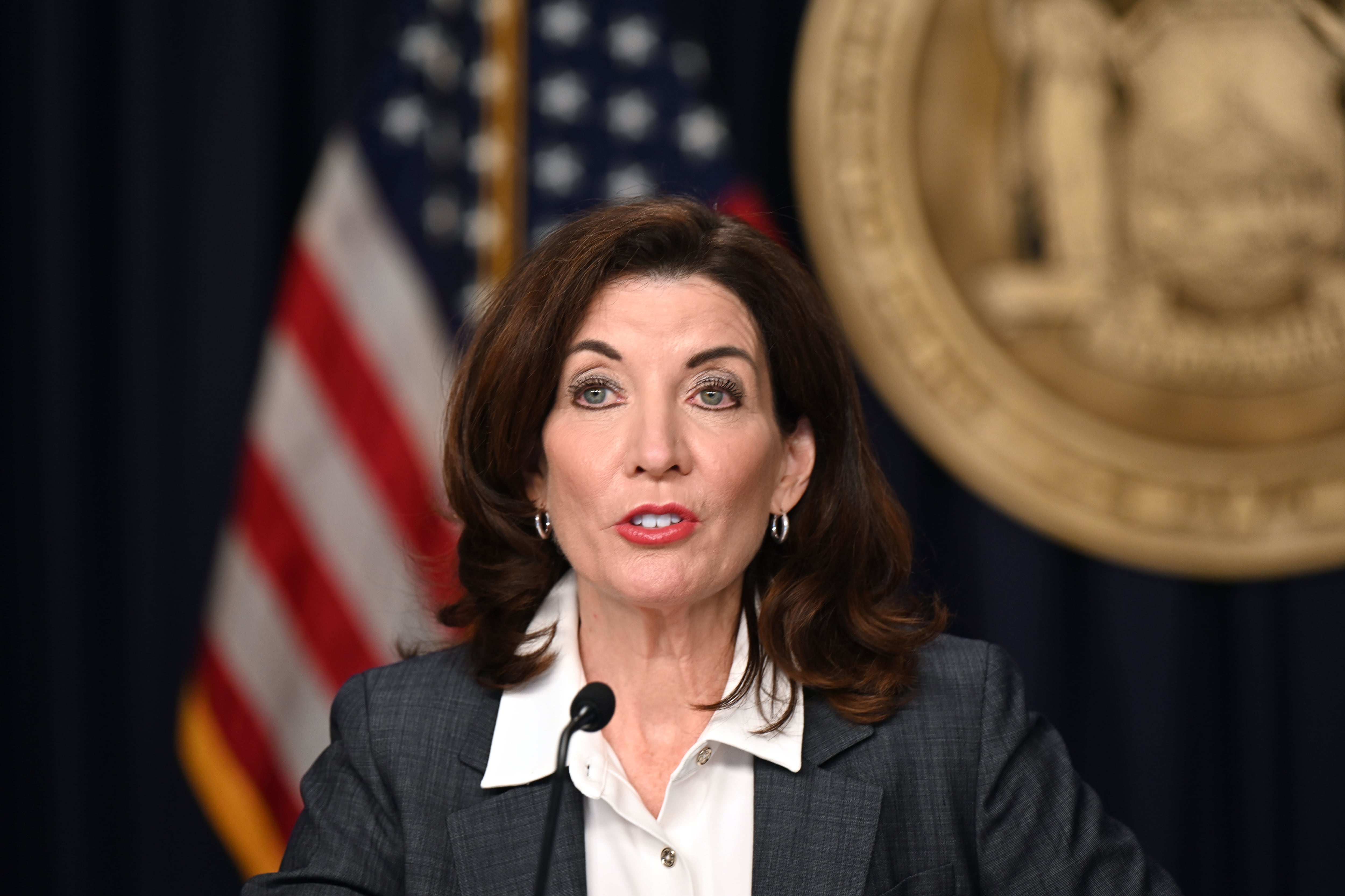 A close up of a woman in front of an American flag.