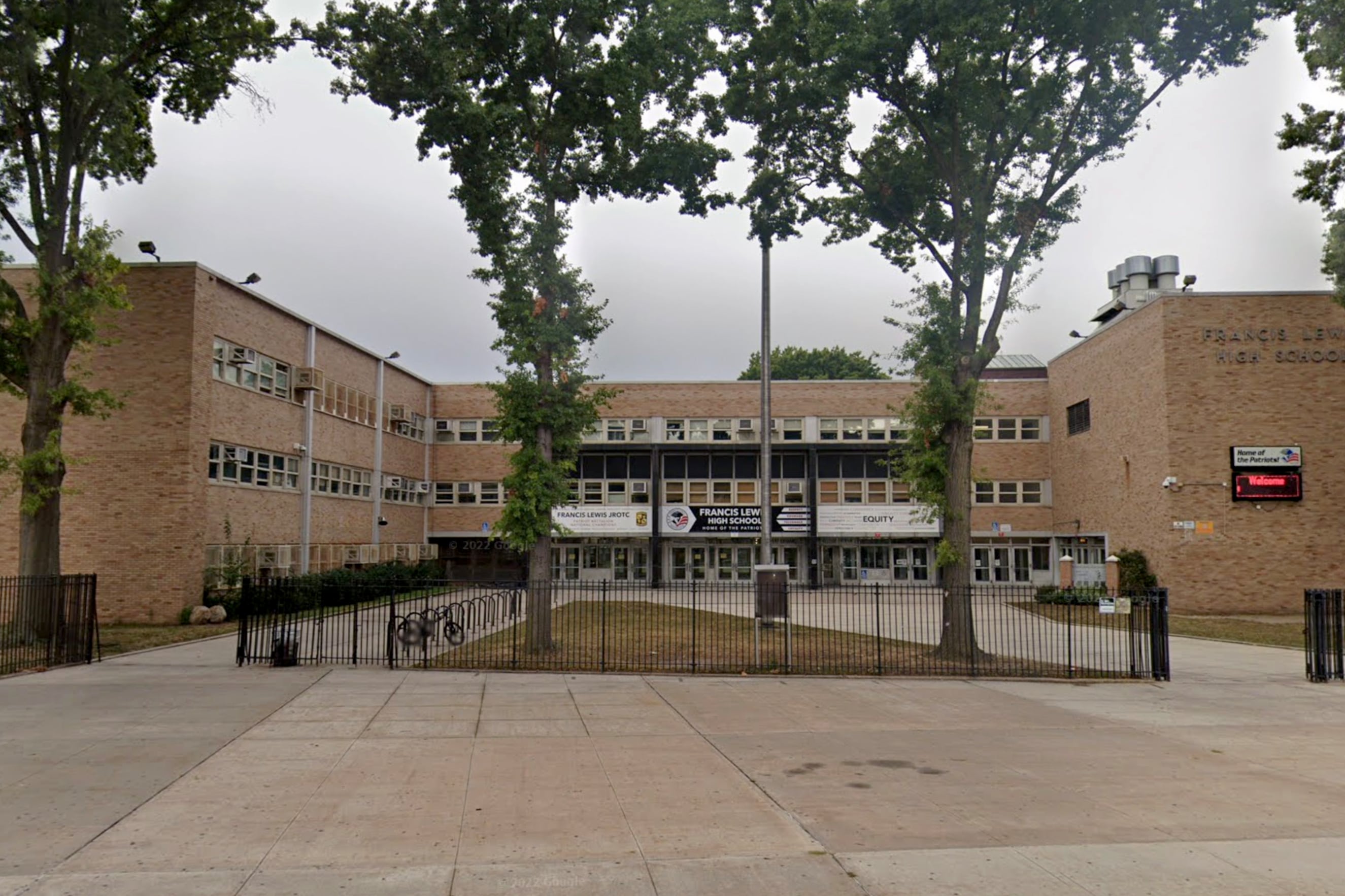The exterior of a brick school building with trees in the middle of a large courtyard