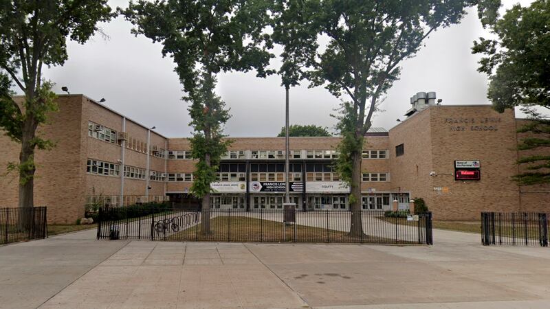 The exterior of a brick school building with trees in the middle of a large courtyard