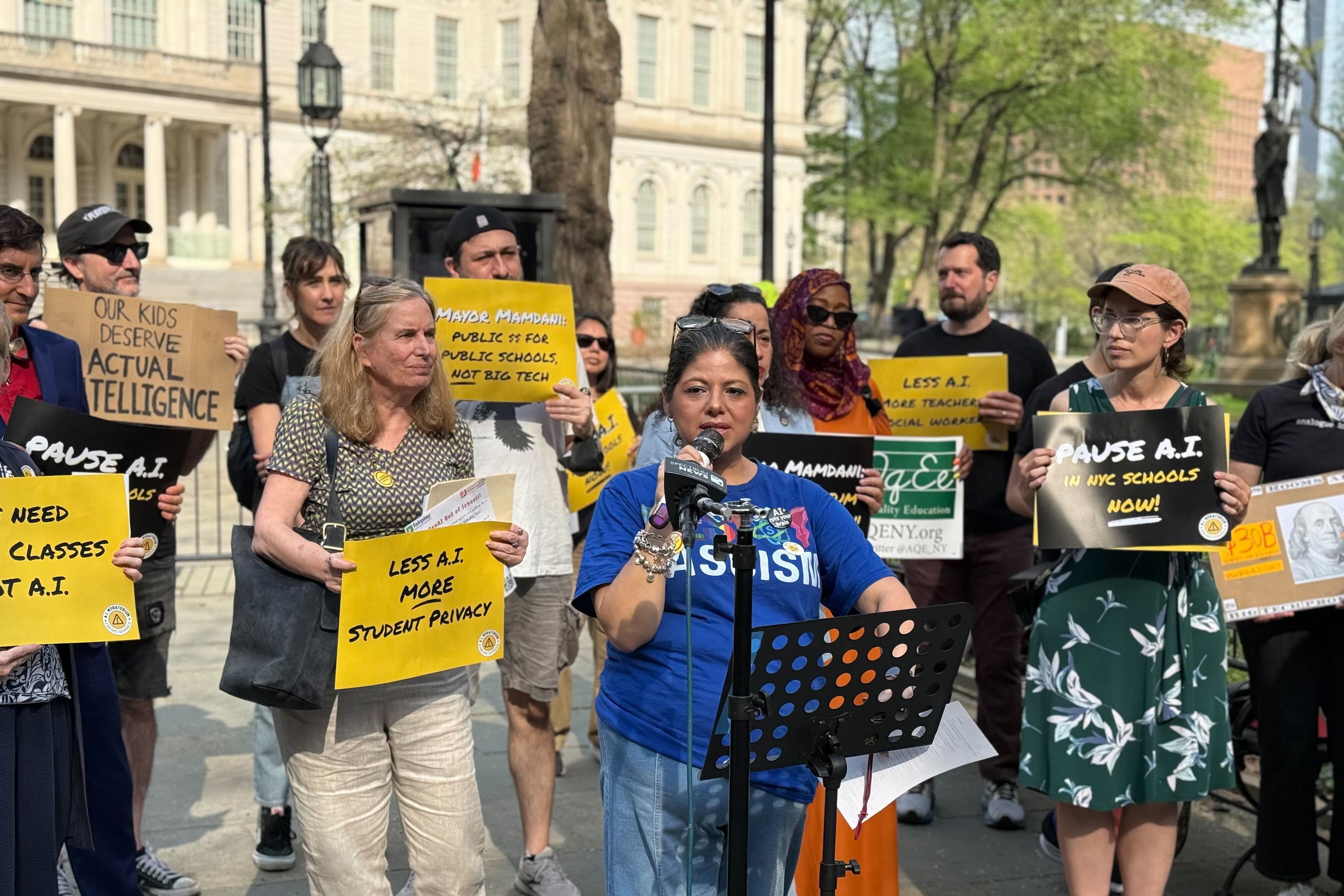 A group of people protest holding yellow signs.