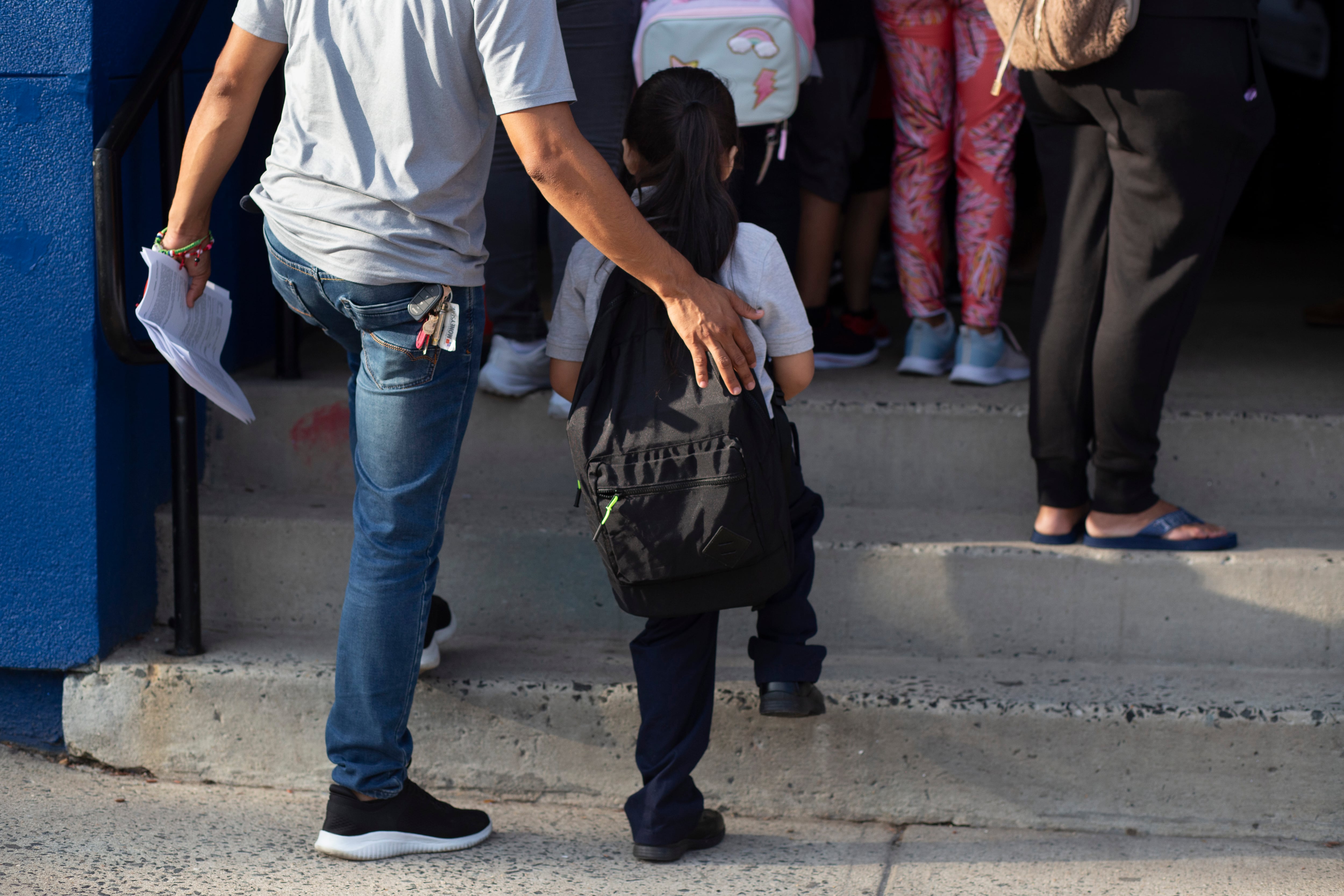 A woman places her arm around a small child’s shoulder.