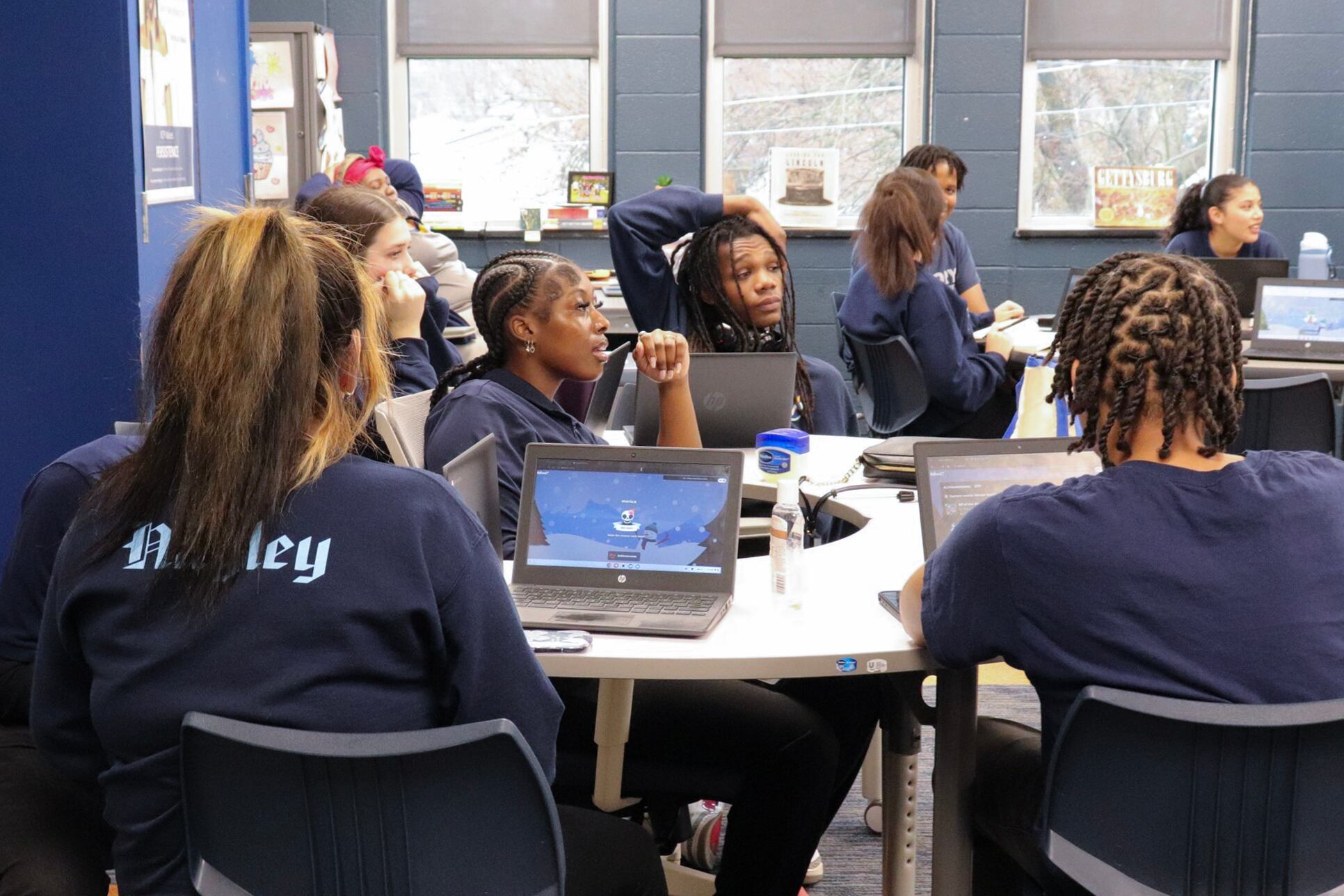 students sit around a table with laptops
