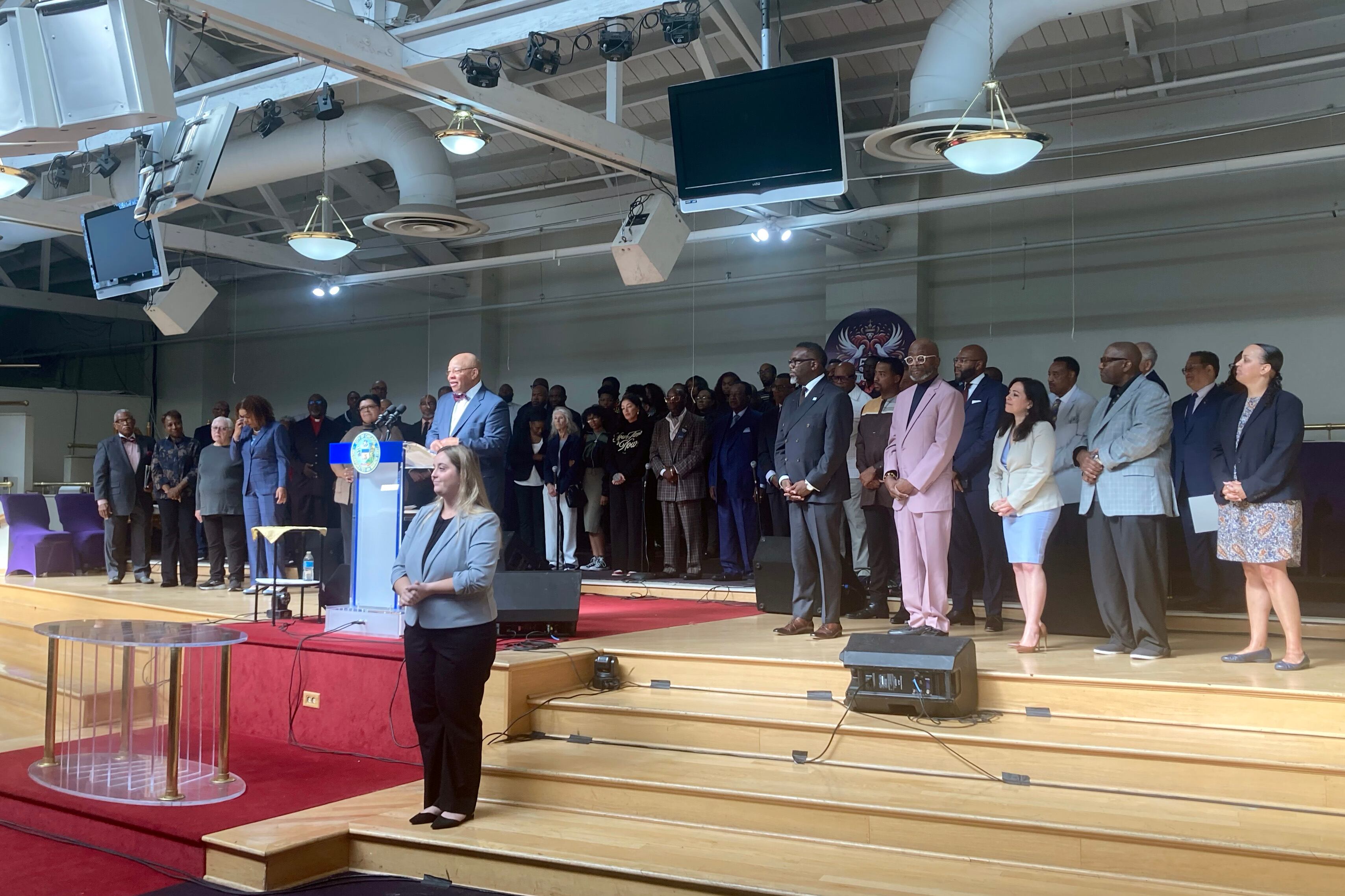 A large group of people in business clothes stand in a line on stage.