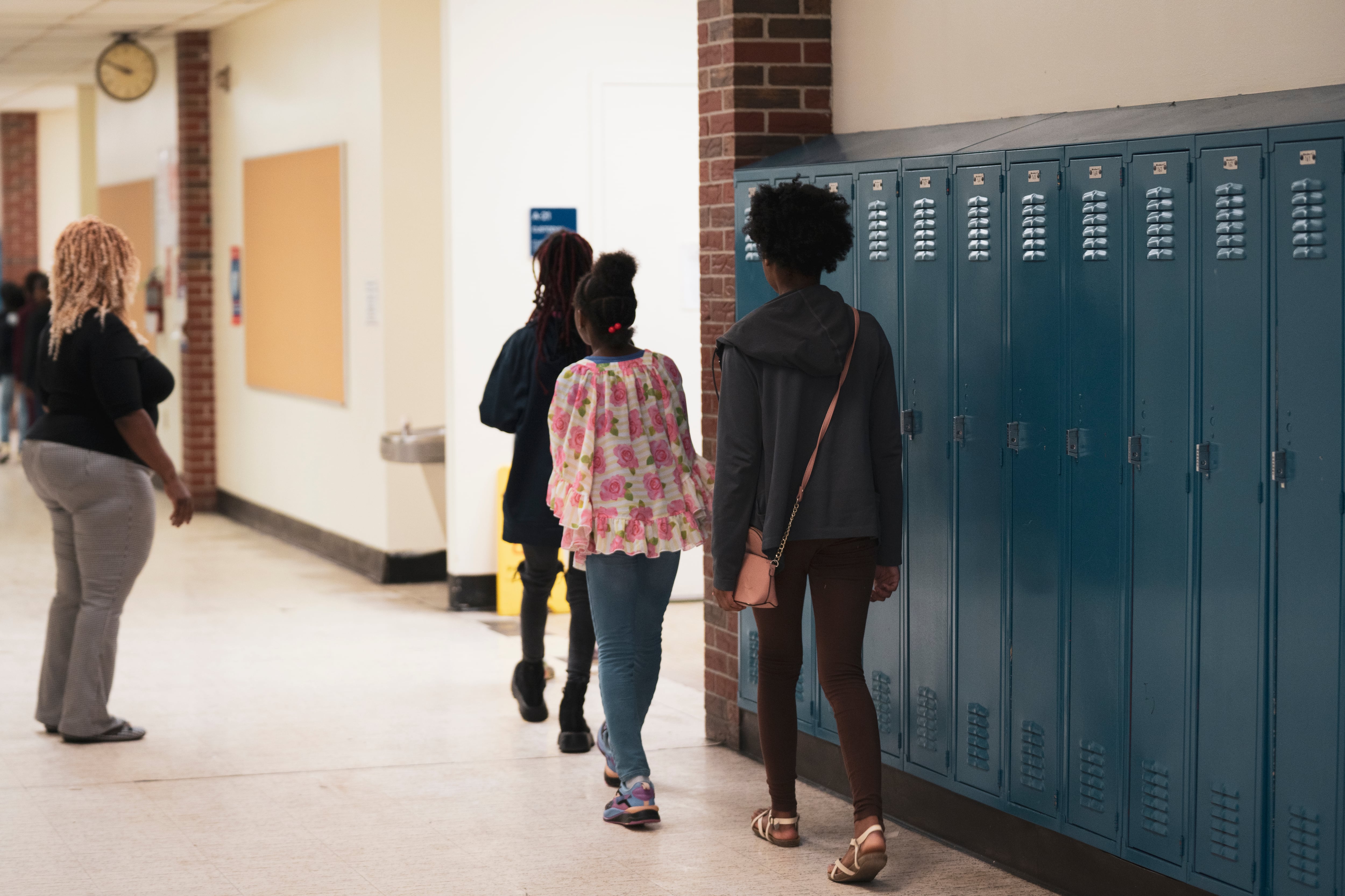 Children walk in a hallway lined with blue lockers.