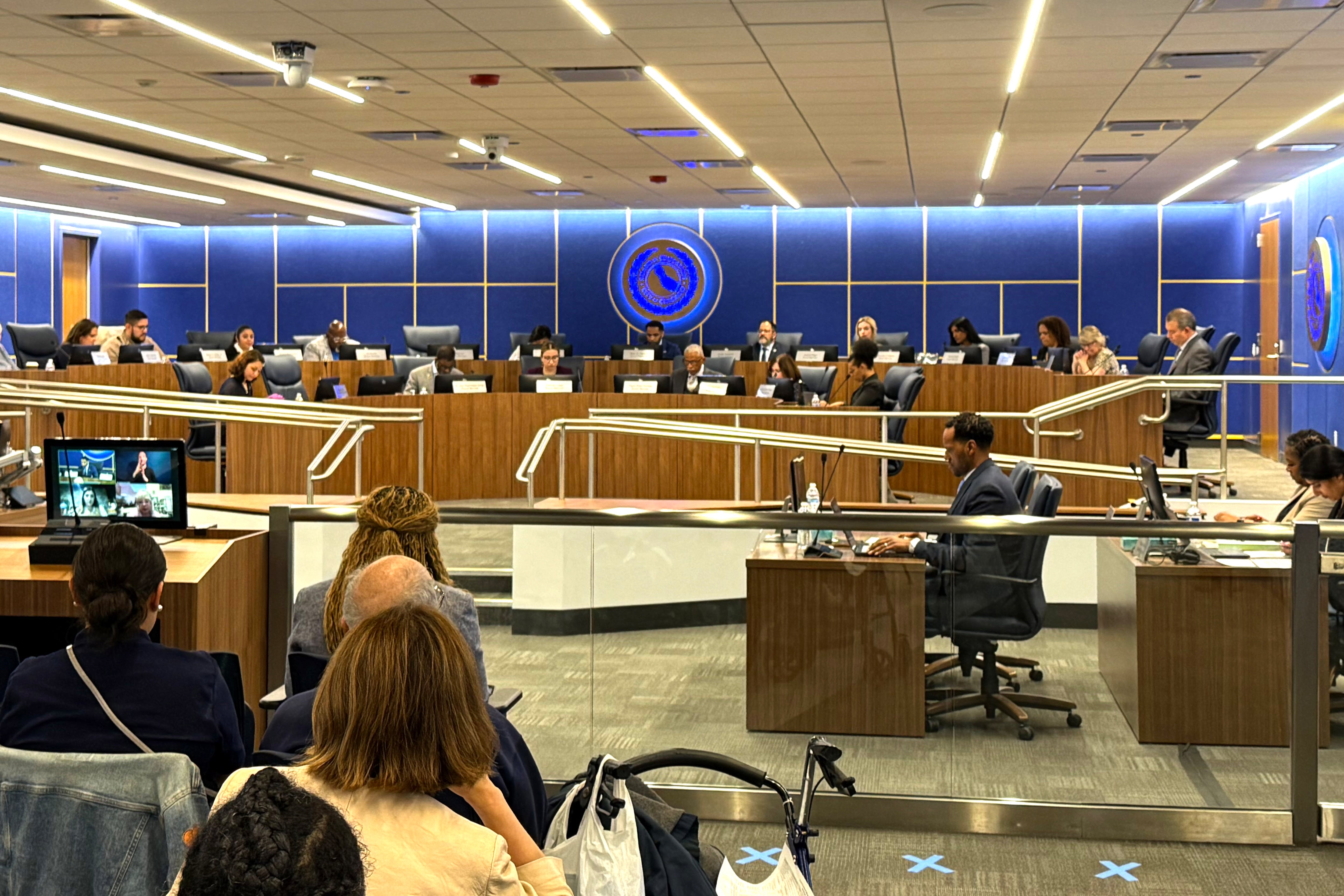 Men and women seated at long desks under a seal.