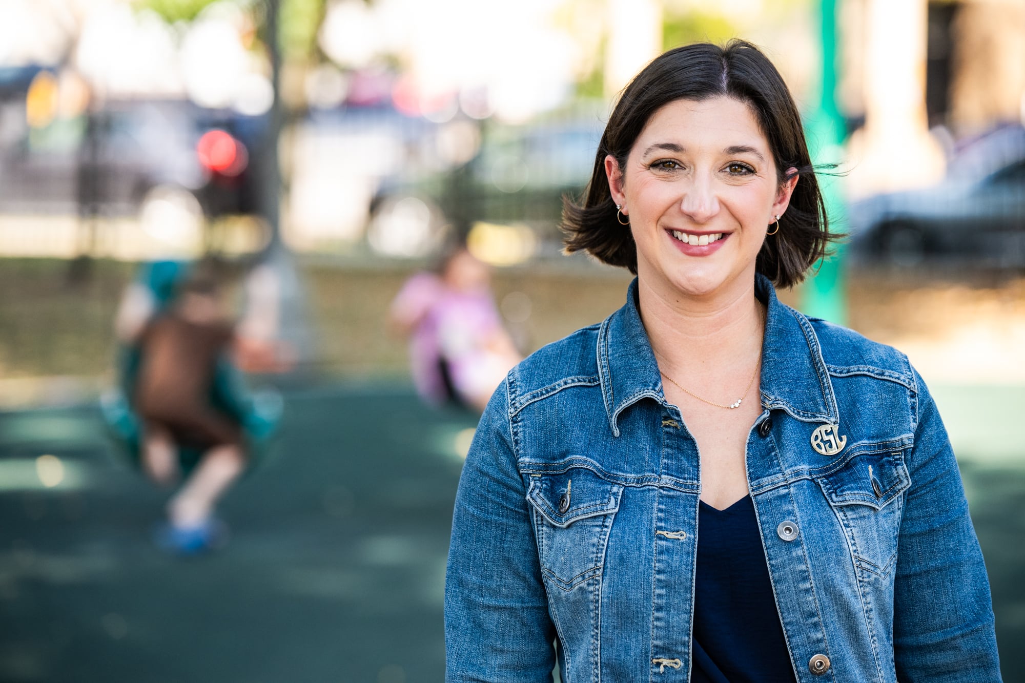 A woman in a jeans jacket stands.