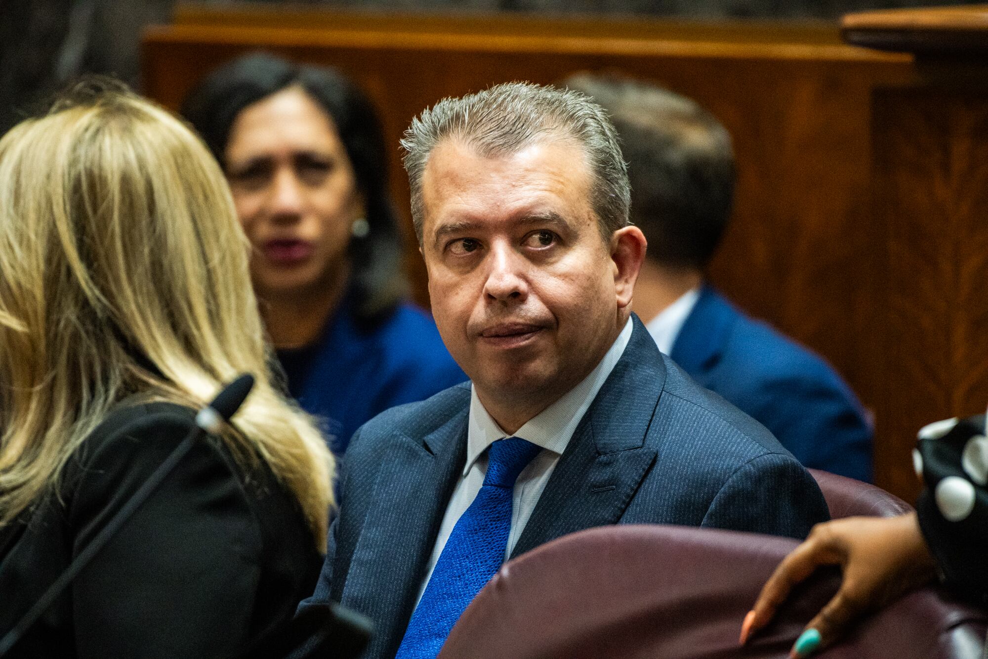 A man wearing a suit sits in a chair.