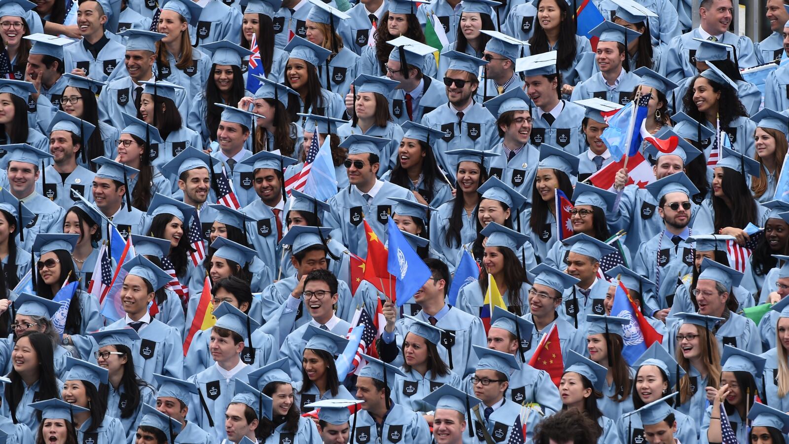 Columbia University graduates wear blue graduation robes and caps.