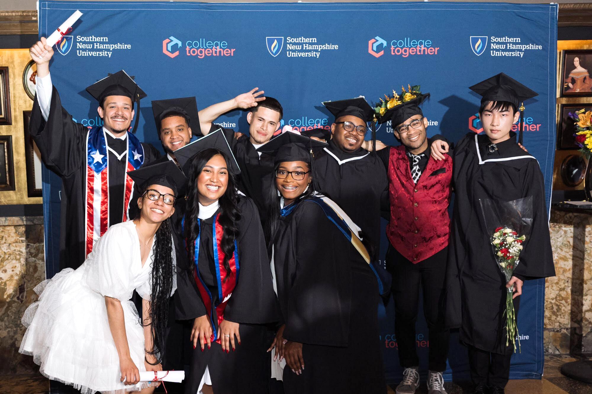 A group of students, mostly in graduation caps and gowns, pose for a photo.