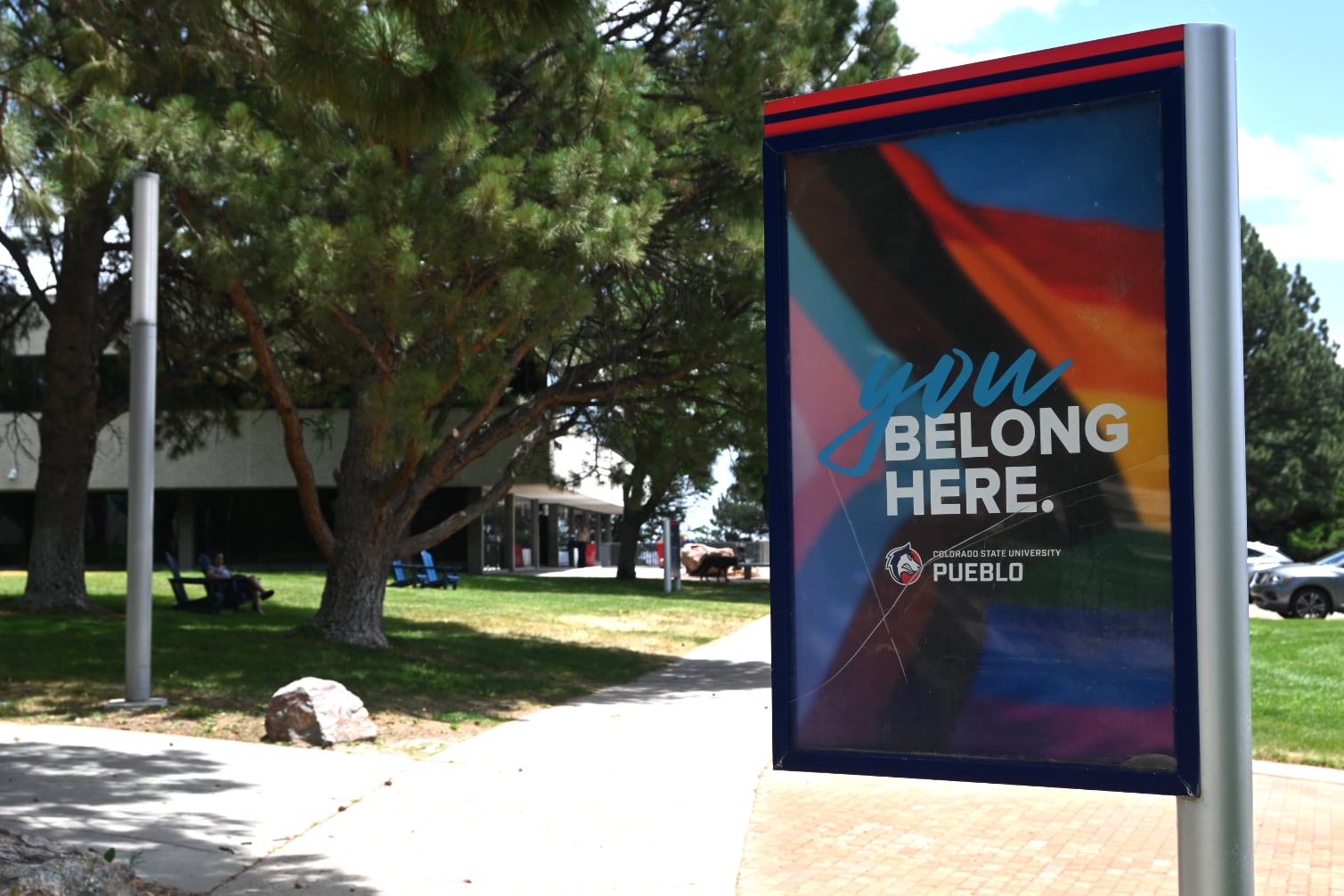 A banner hangs on a pole on a scenic campus.
