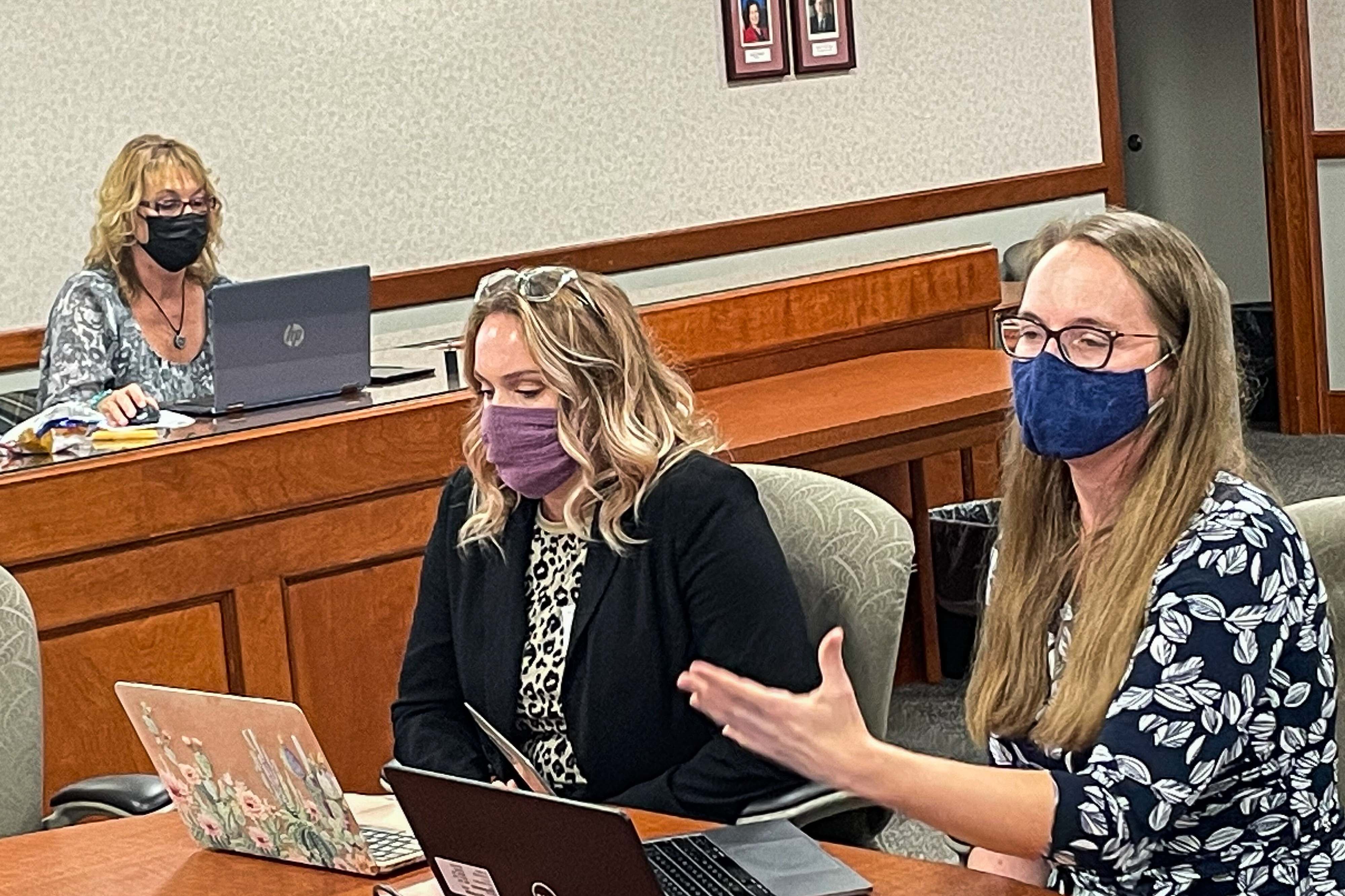 Michigan Teacher of the Year Leah Porter  addresses the state Board of Education during an October meeting. She is seated at the head of a conference table with Kacie Hook of Roscommon Middle School, who is the Teacher of the Year for Region 2. Both have open laptops in front of them.