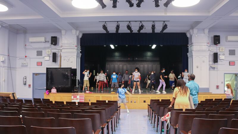 Students stand on a stage in an auditorium.