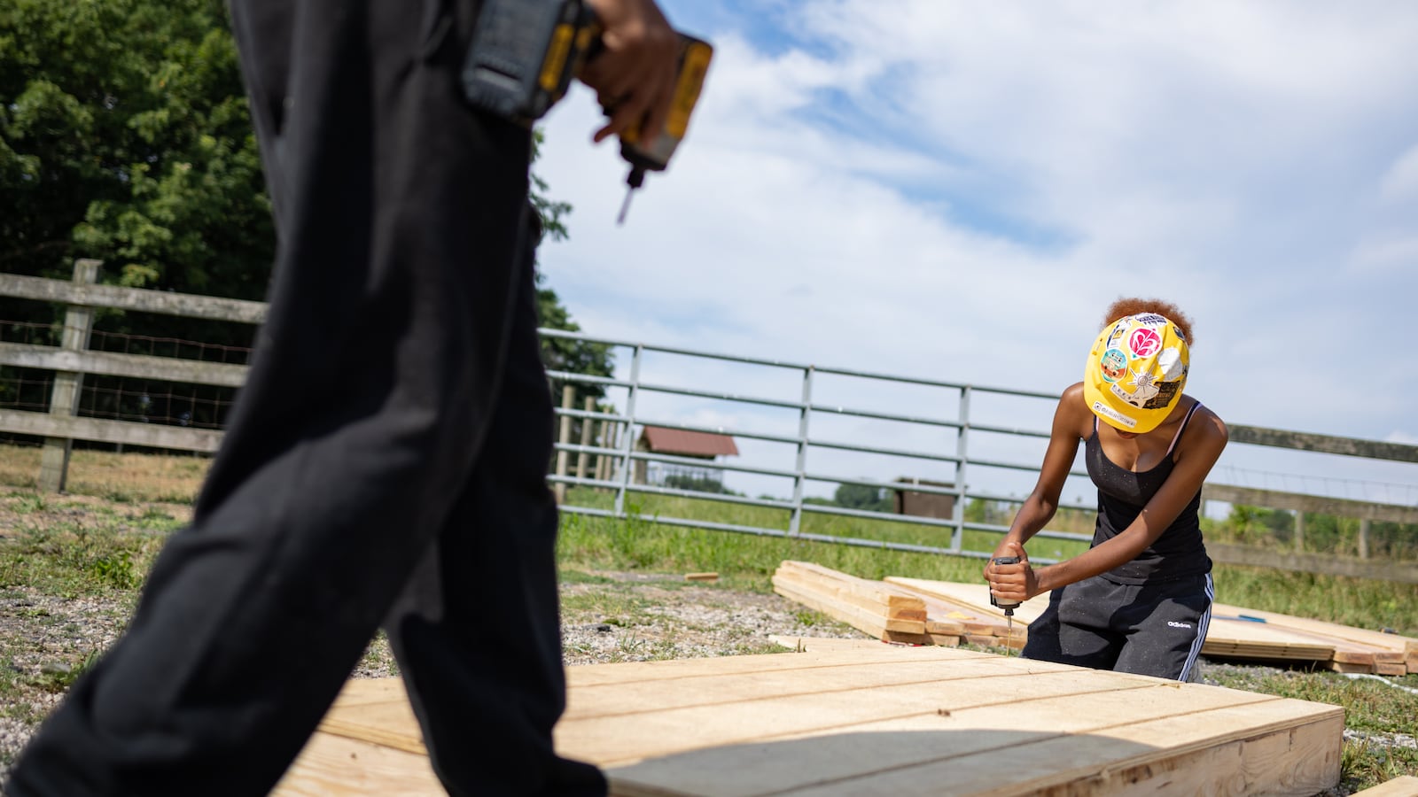 Two students work on constructing a shed, working with power drills.