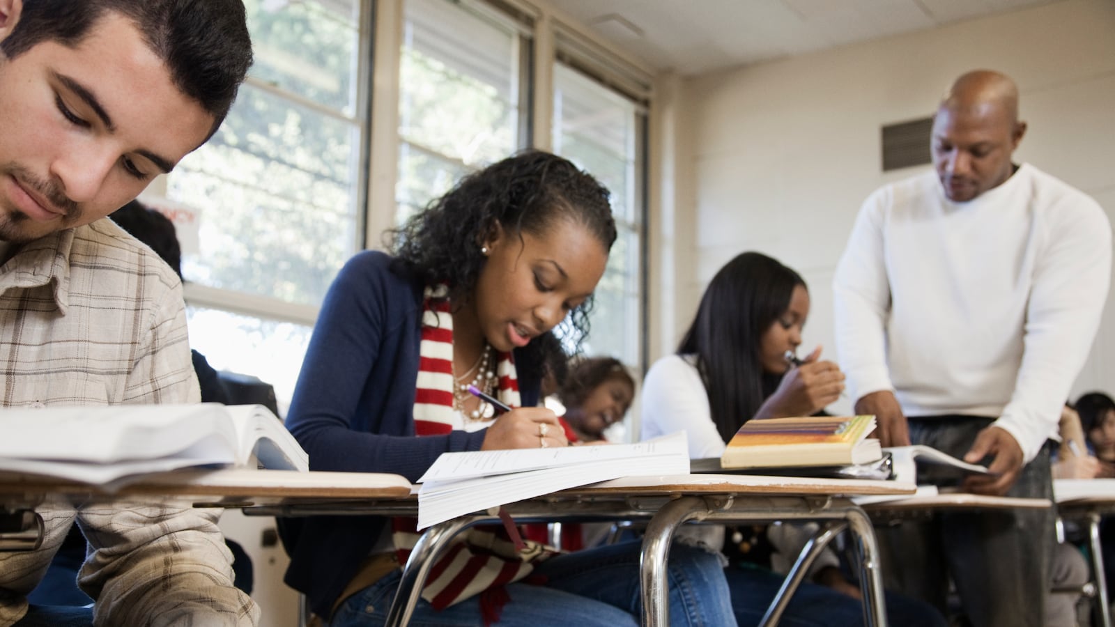 A teacher walks around a high school classroom helping his students.