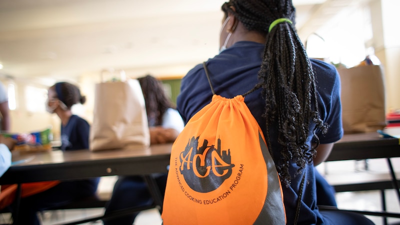 A student wearing an orange bag attends an after-school club meeting.