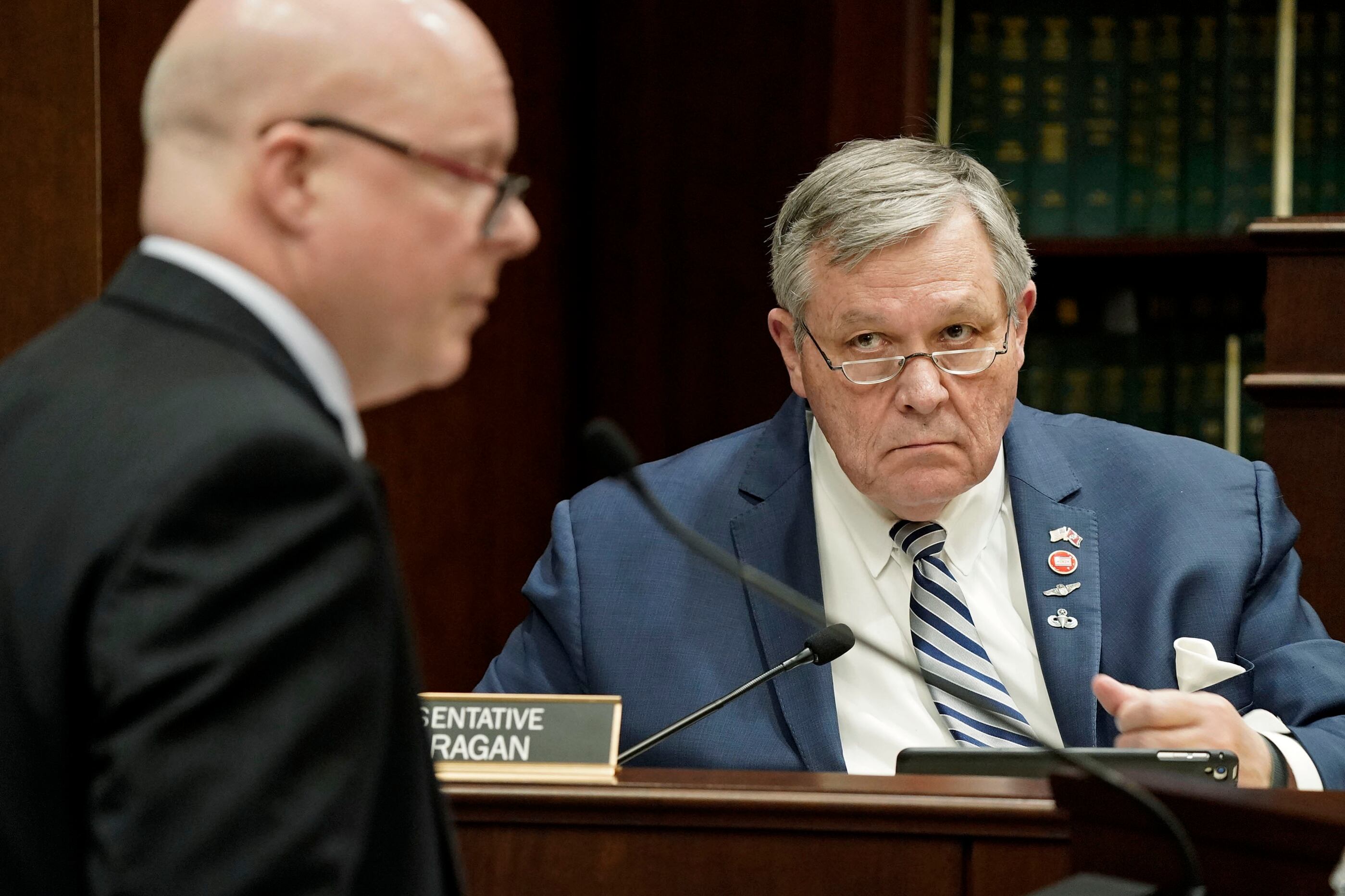 Two men wearing business suits in a legislative chamber