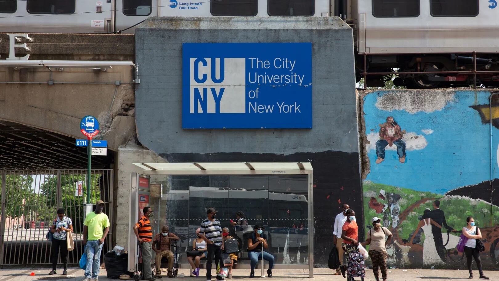 A sign for a CUNY campus with NYC silver subway trains running above ground over it.