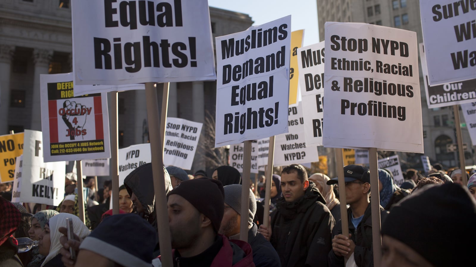 Muslim-Americans hold signs as they protest the continued infiltration and monitoring of local Muslims and Muslim community organizations.