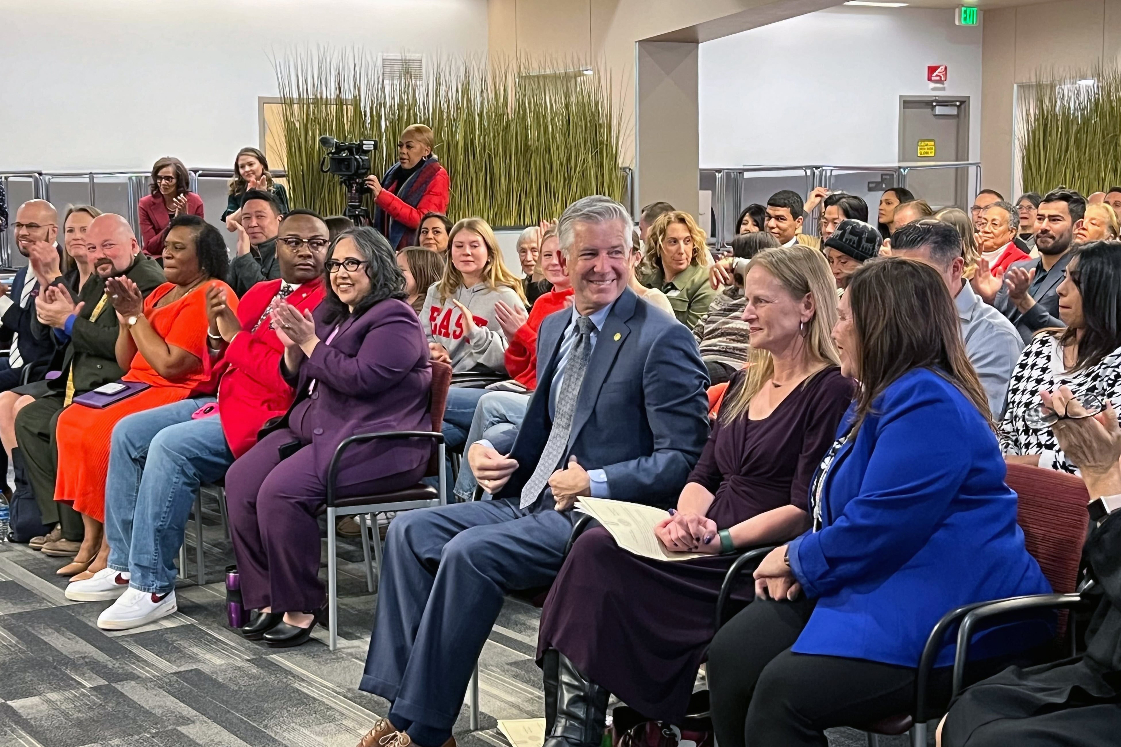 A large crowd of people sit in chairs during a ceremony.