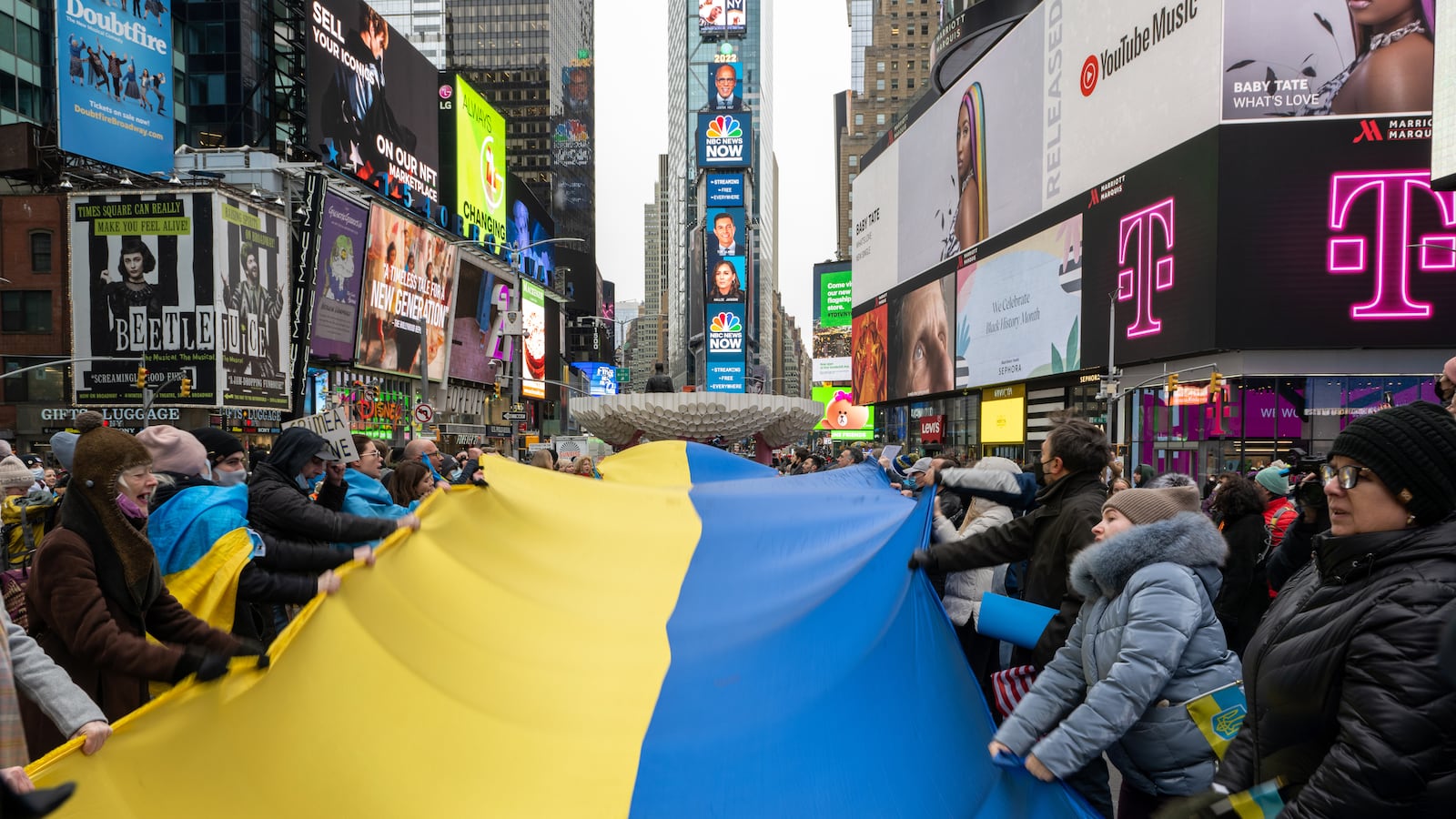 Group of people holding a large Ukrainian flag gather for a “Stand With Ukraine” rally in Times Square, New York City.