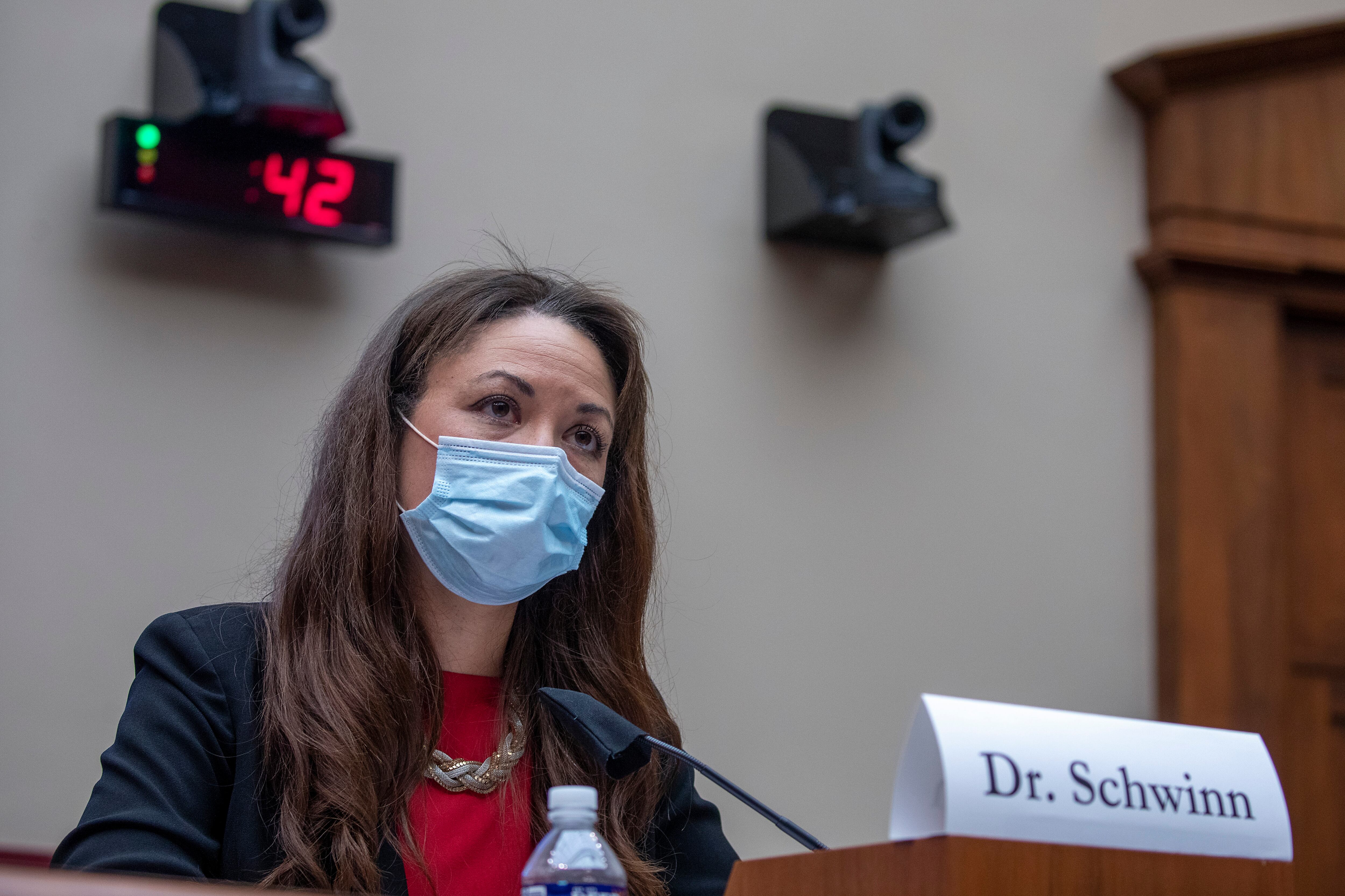 masked woman speaking at a podium