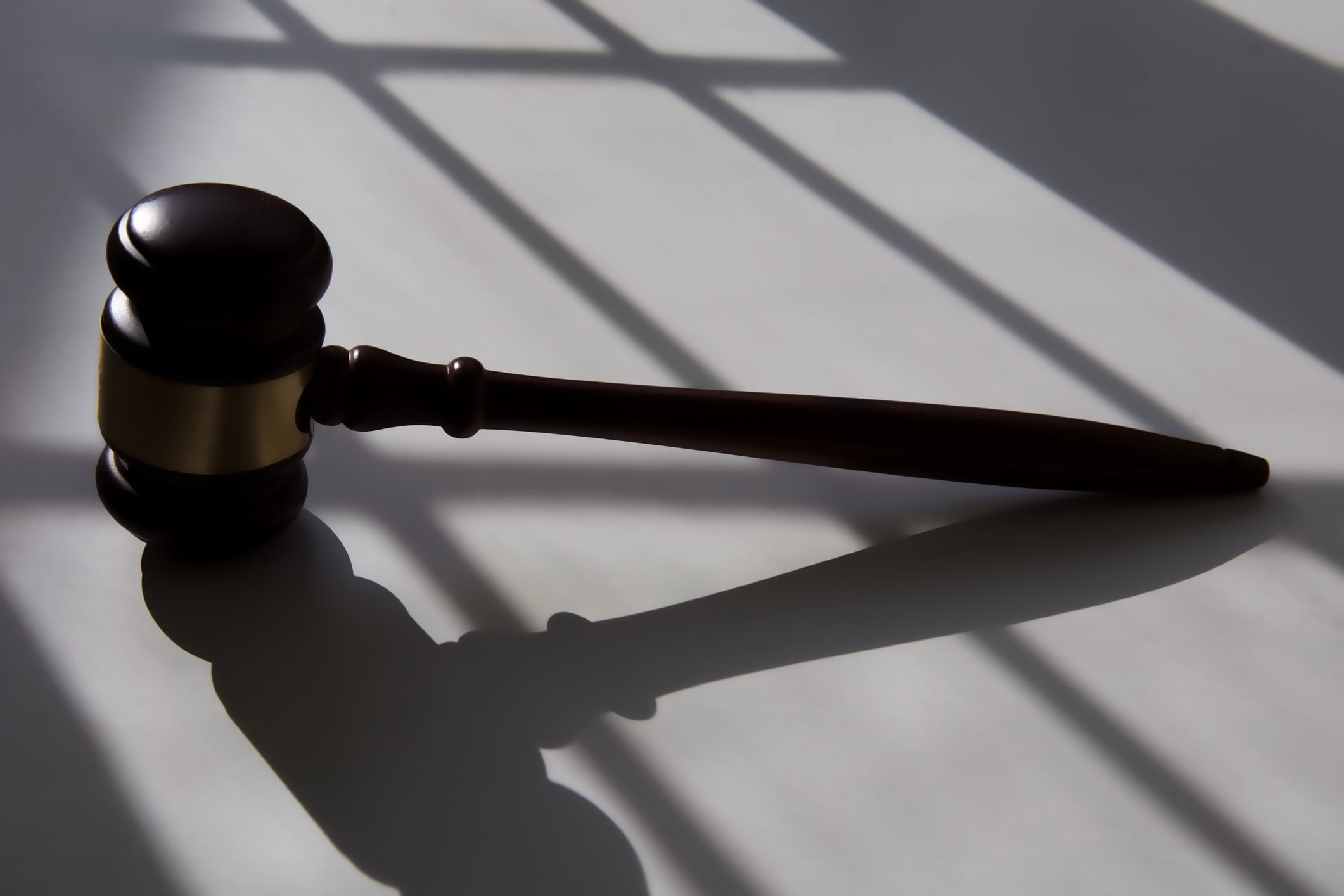 A gavel casts a shadow on top of a white table.