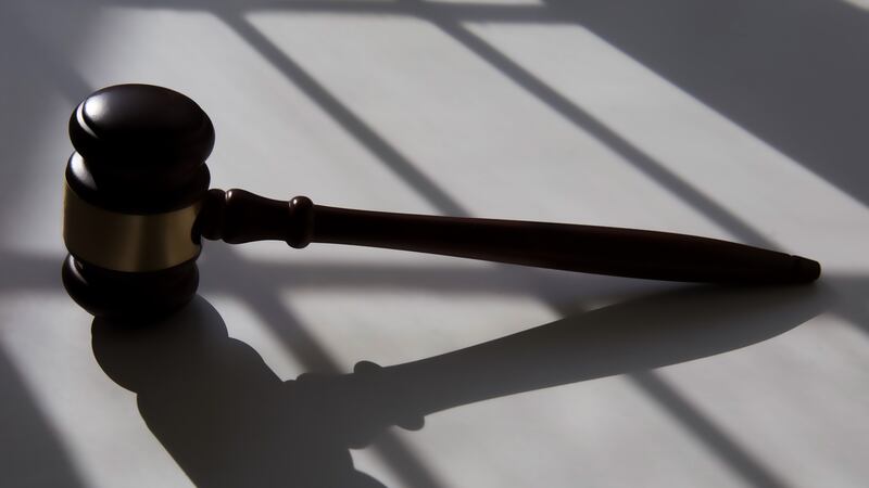 A gavel casts a shadow on top of a white table.