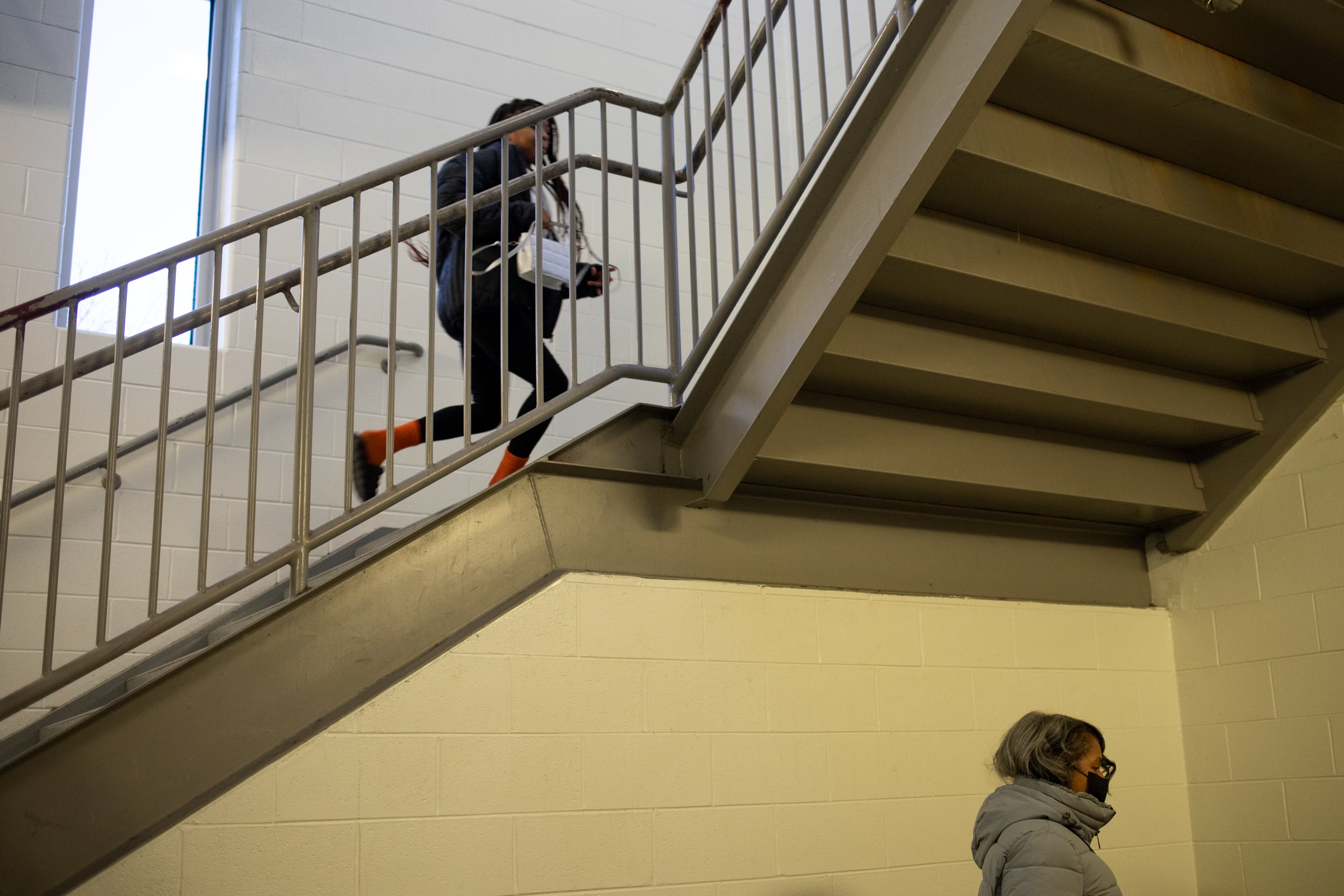A student runs up the stairs while an adult is seen in a lower level.