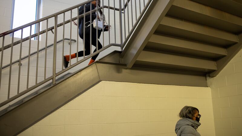 A student runs up the stairs while an adult is seen in a lower level.
