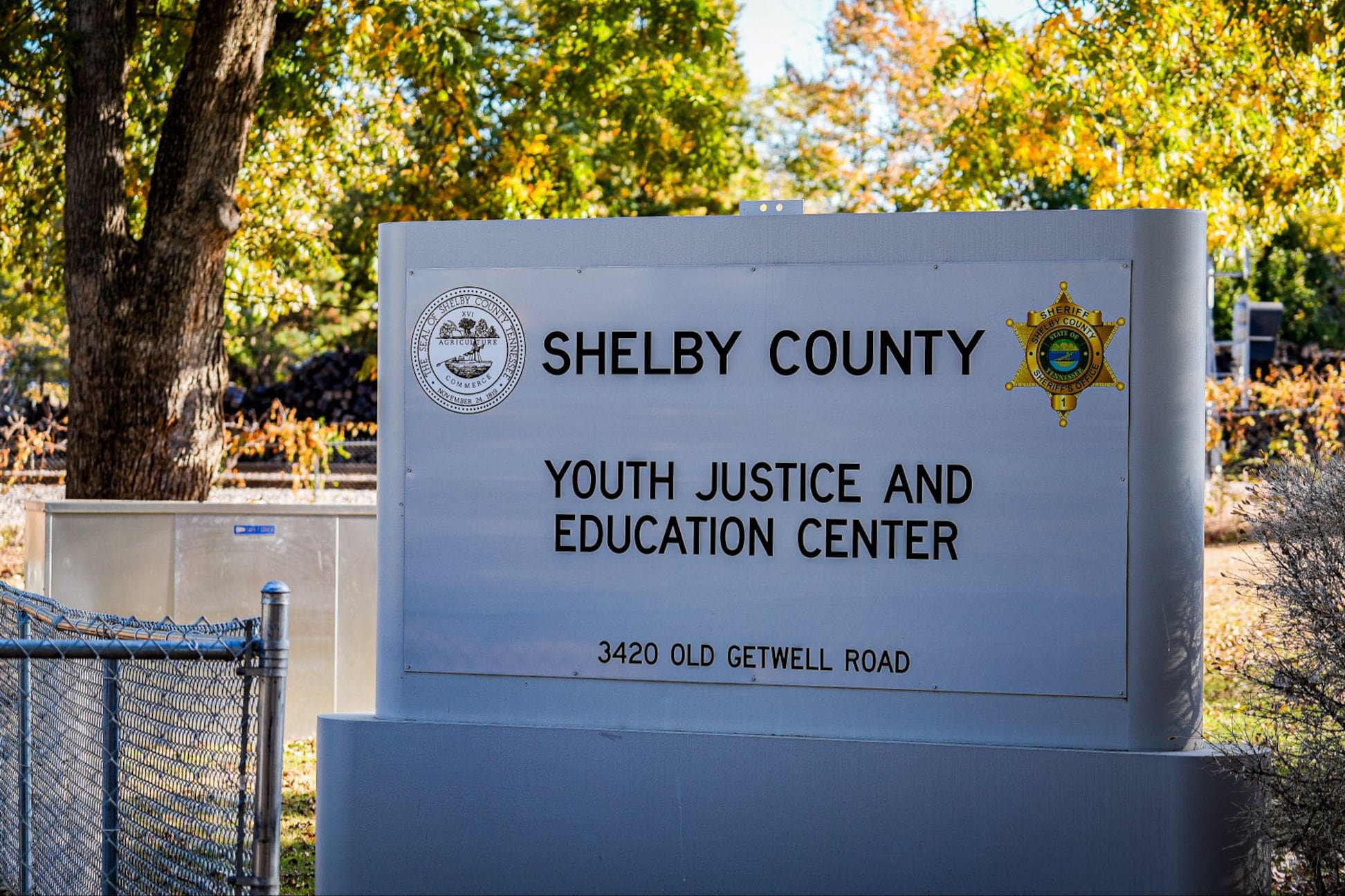 A stone sign outside with greenery in the background.