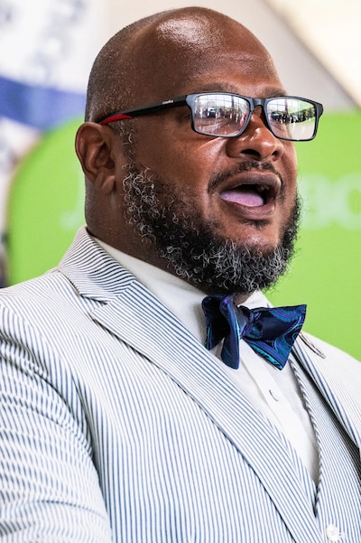 A man with glasses and a pinstripe suit jacket speaks.