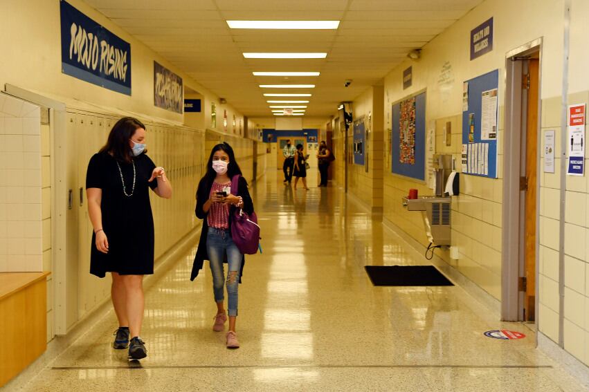 A teacher walks next to a student in a middle school hallway.