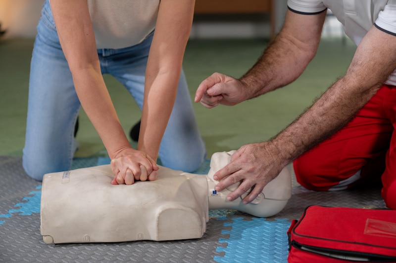Two people put their hands over a dummy.