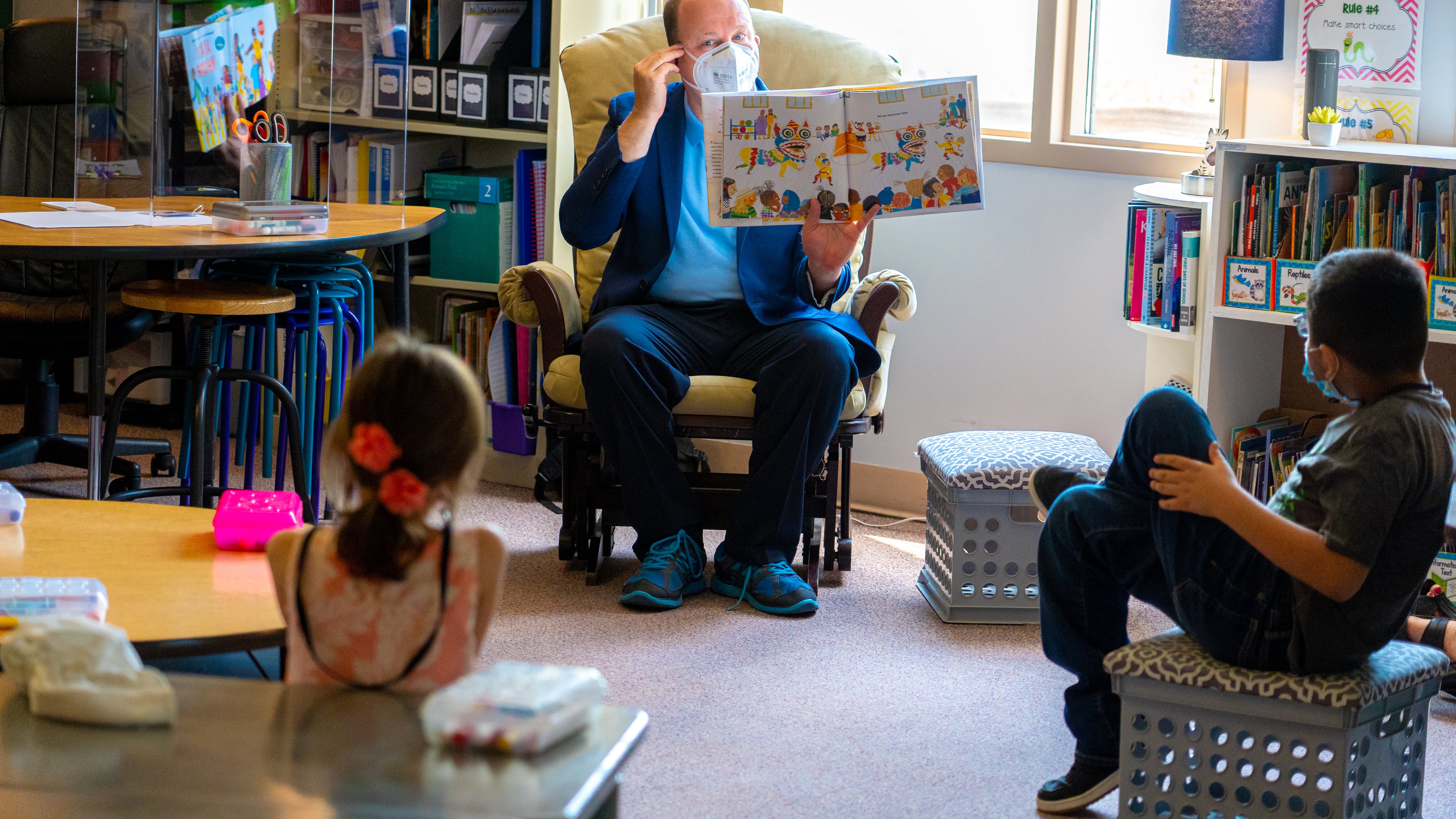 Colorado Gov. Jared Polis reads a story to young schoolchildren in a classroom while wearing a mask during the COVID-19 pandemic.