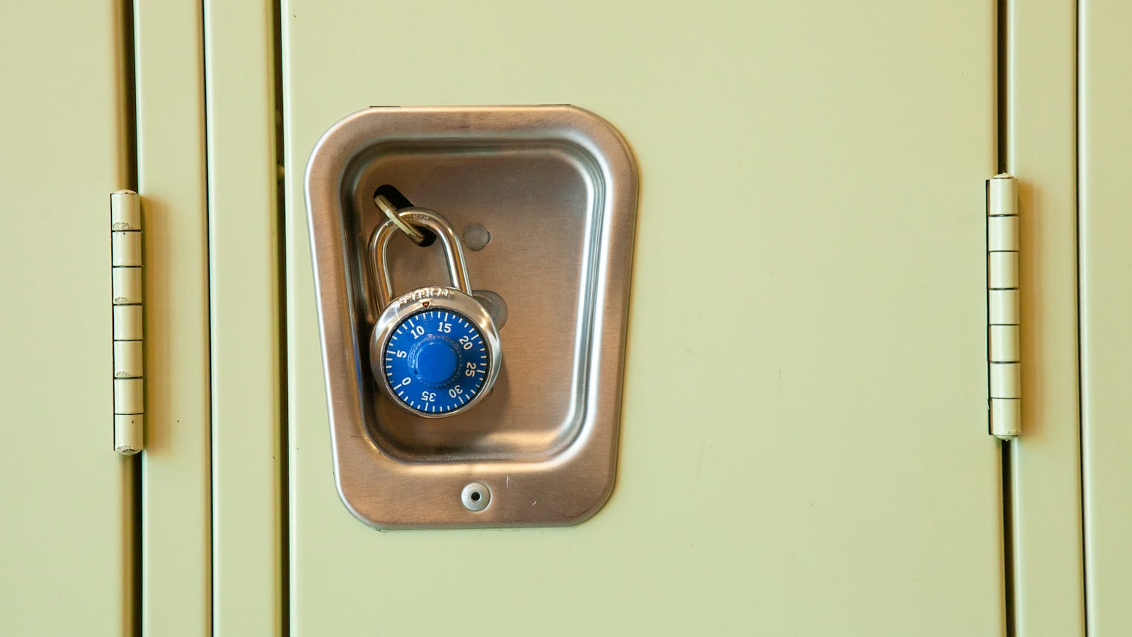 A close of image of a yellow high school locker with a blue pad lock.