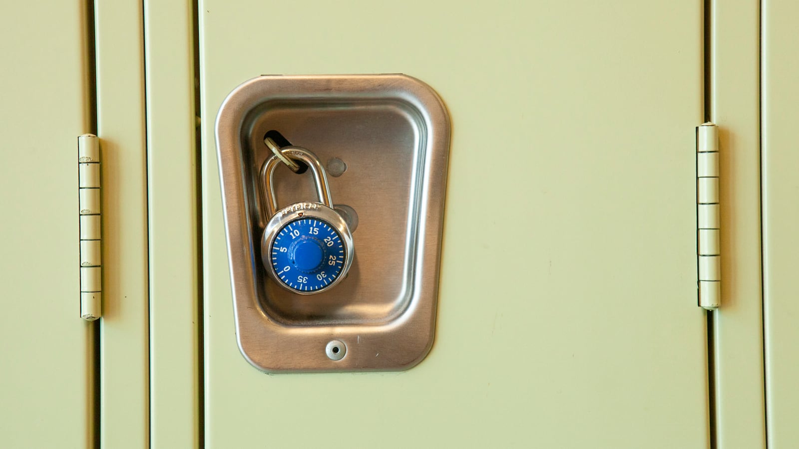 A close of image of a yellow high school locker with a blue pad lock. 