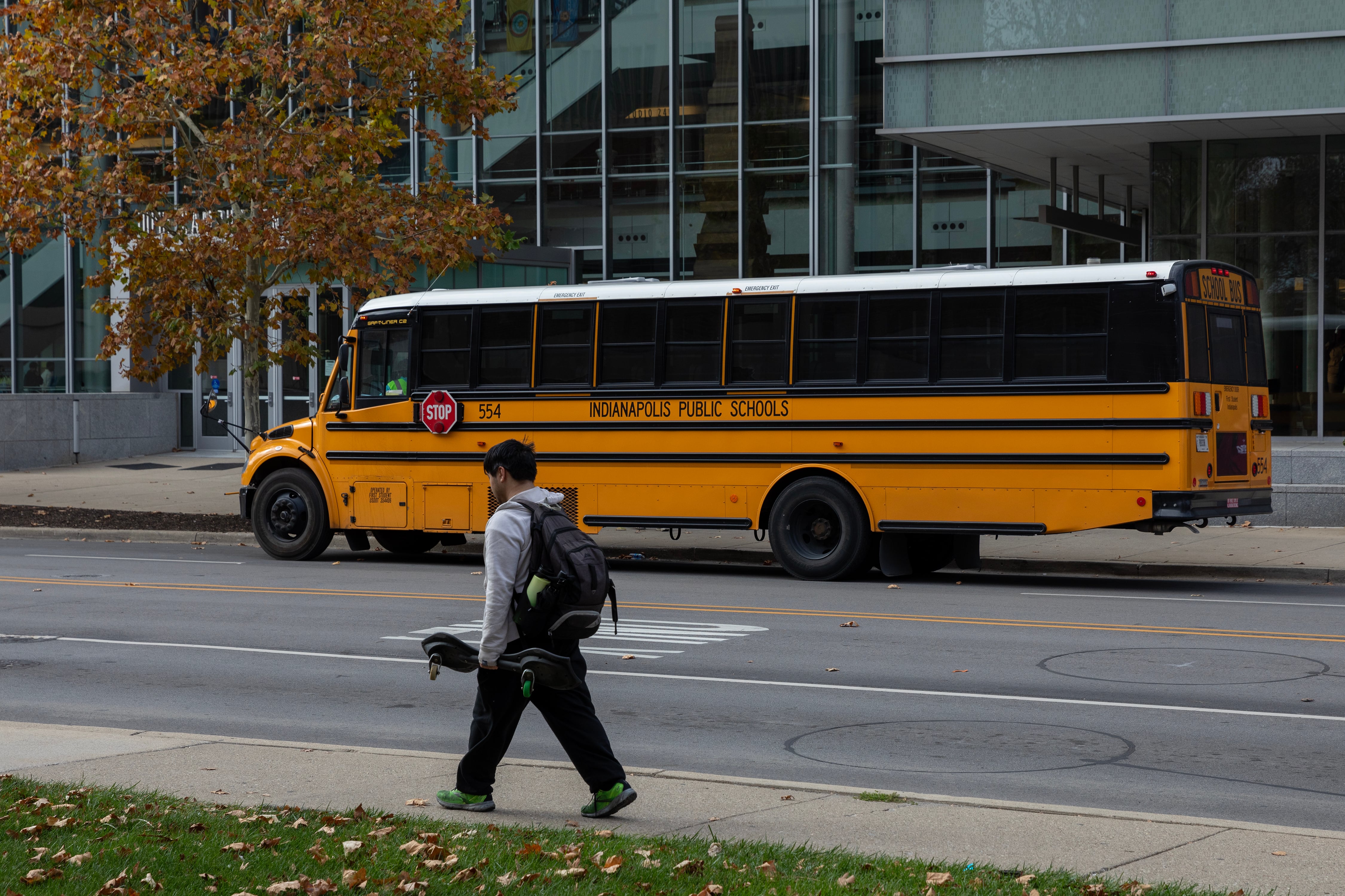 A yellow and black school bus is parked on the side of a street with buildings in the background.