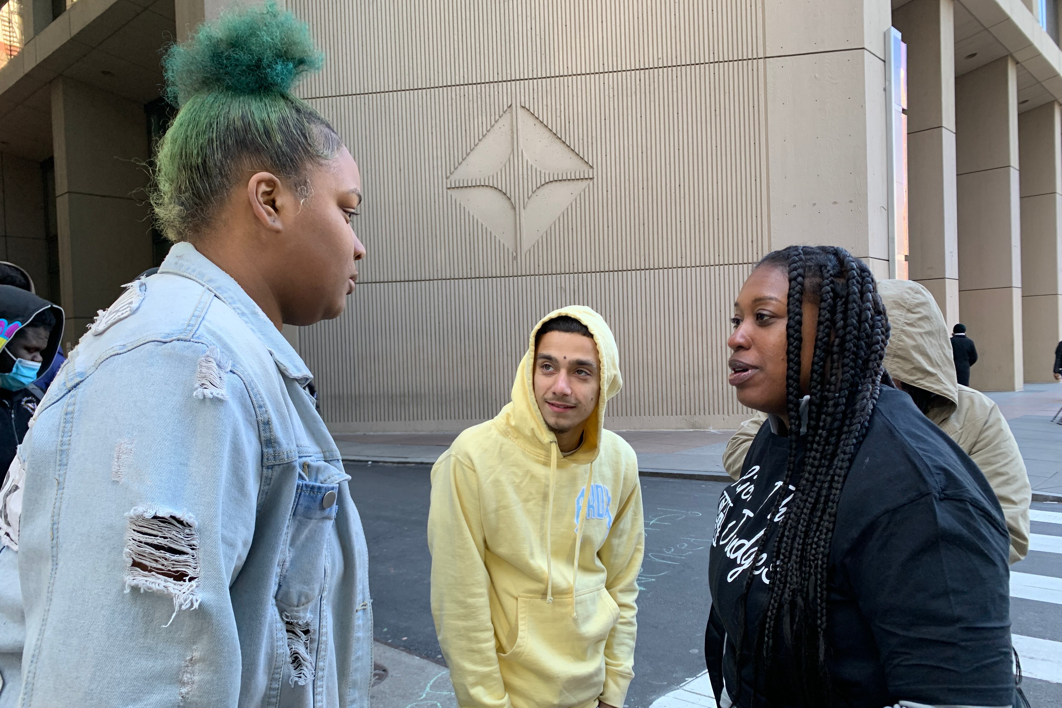 Three young people talking in front of a crosswalk