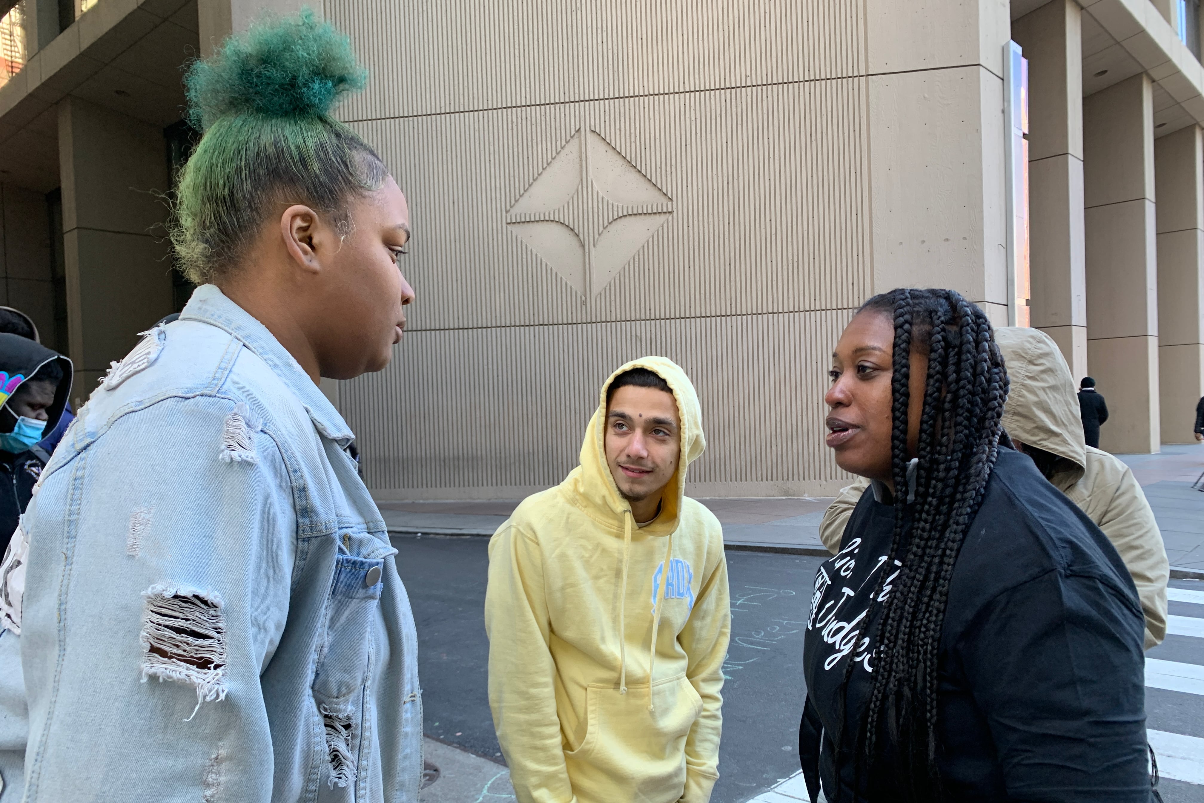 Three young people talking in front of a crosswalk